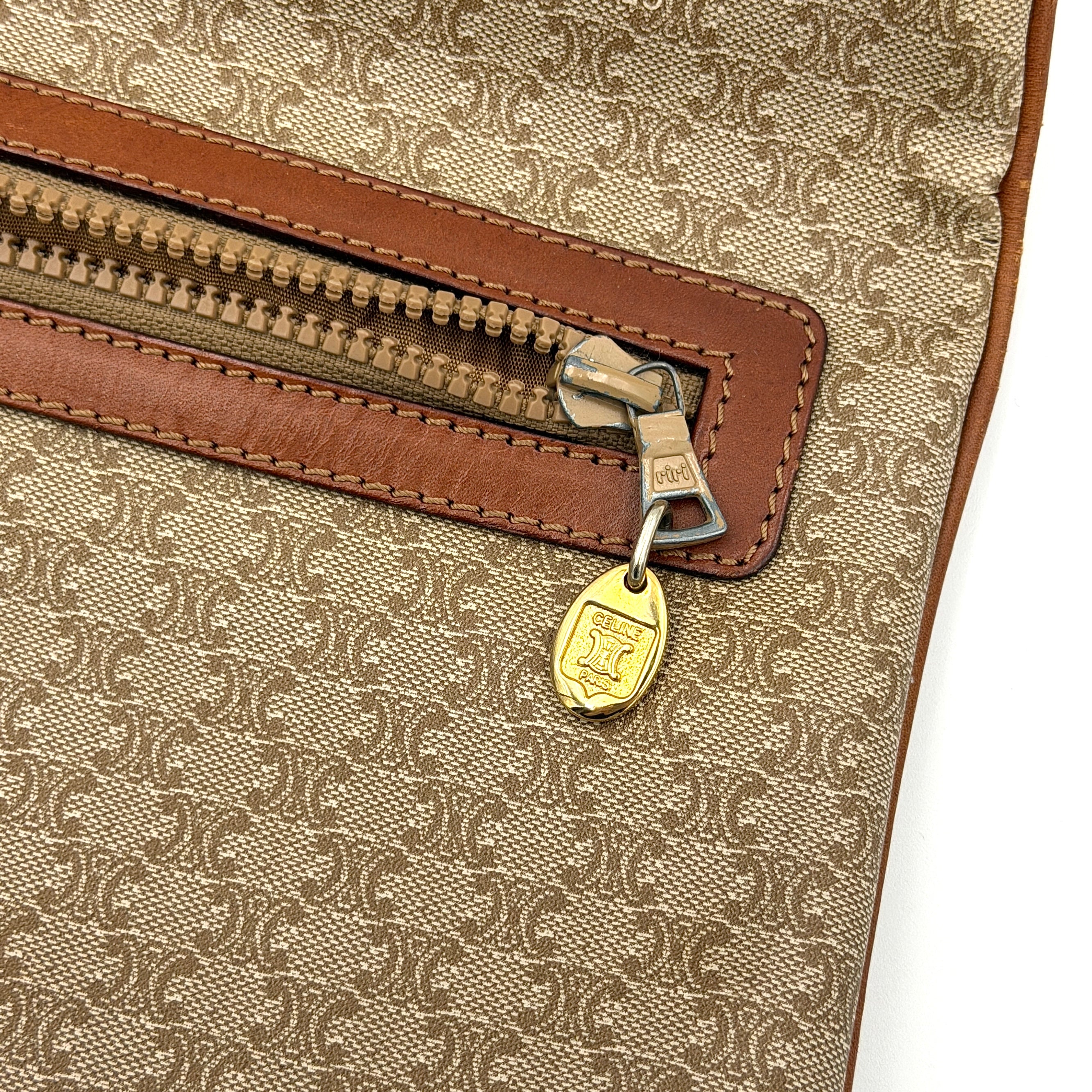 The Celine Macadam Clutch Bag in beige, featuring the iconic monogram canvas and tan leather trim, shown neatly closed with its signature emblem on the flap.