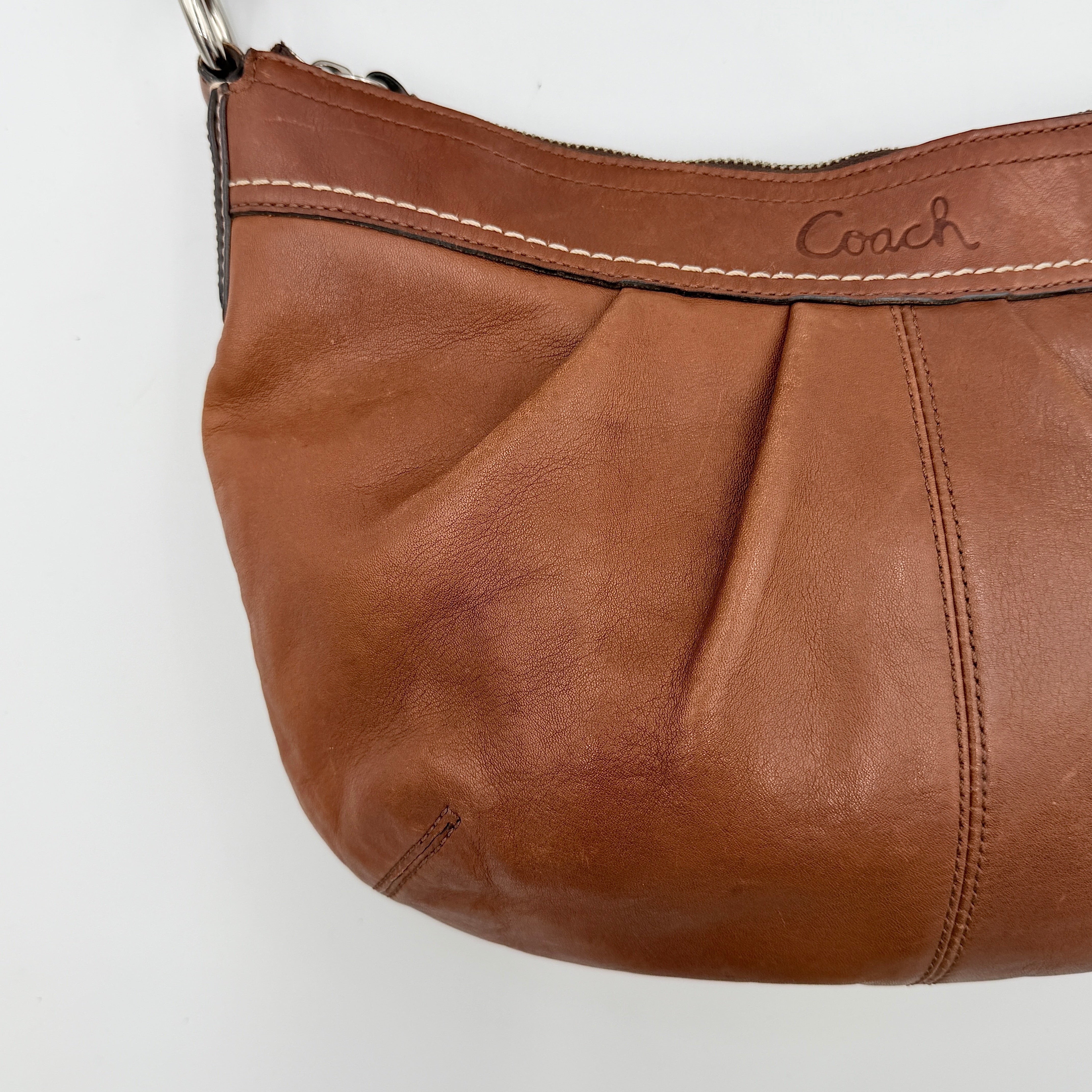 Coach Soho Hobo brown leather shoulder bag with pleated detailing and silver hardware, shown on a white background.