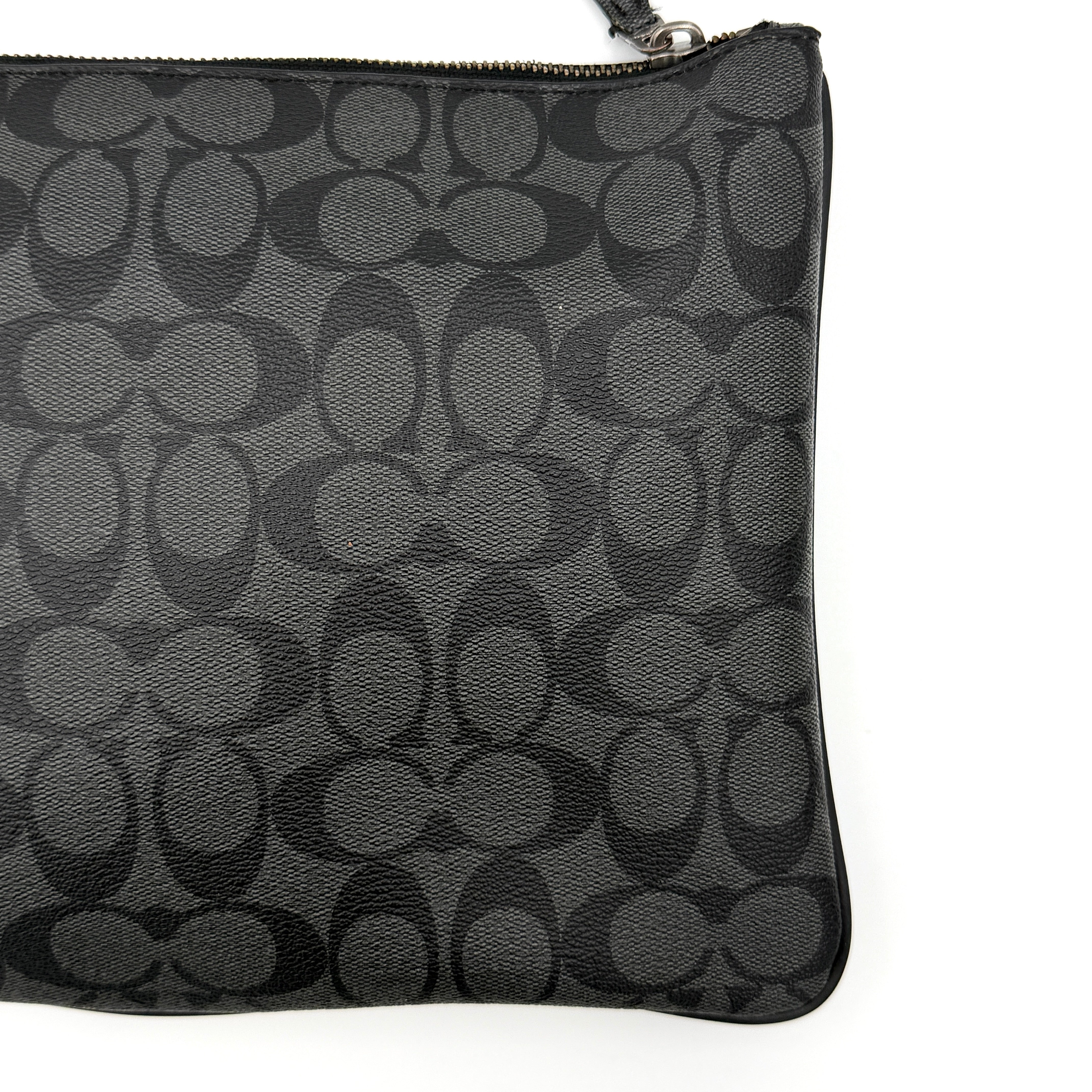 Coach Signature large pouch in black coated canvas with navy and cream varsity stripes, shown from the front with a zip top.