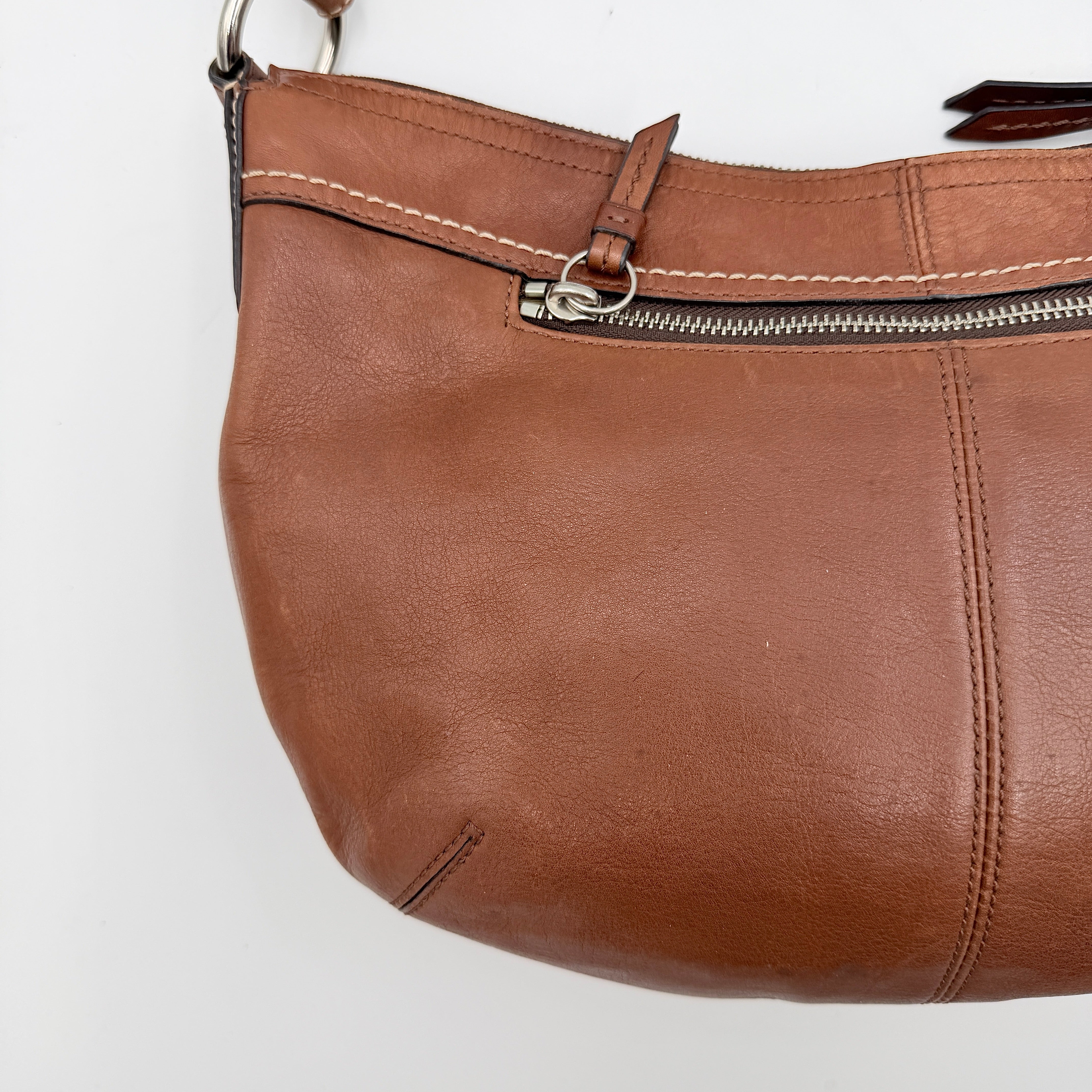 Coach Soho Hobo brown leather shoulder bag with pleated detailing and silver hardware, shown on a white background.