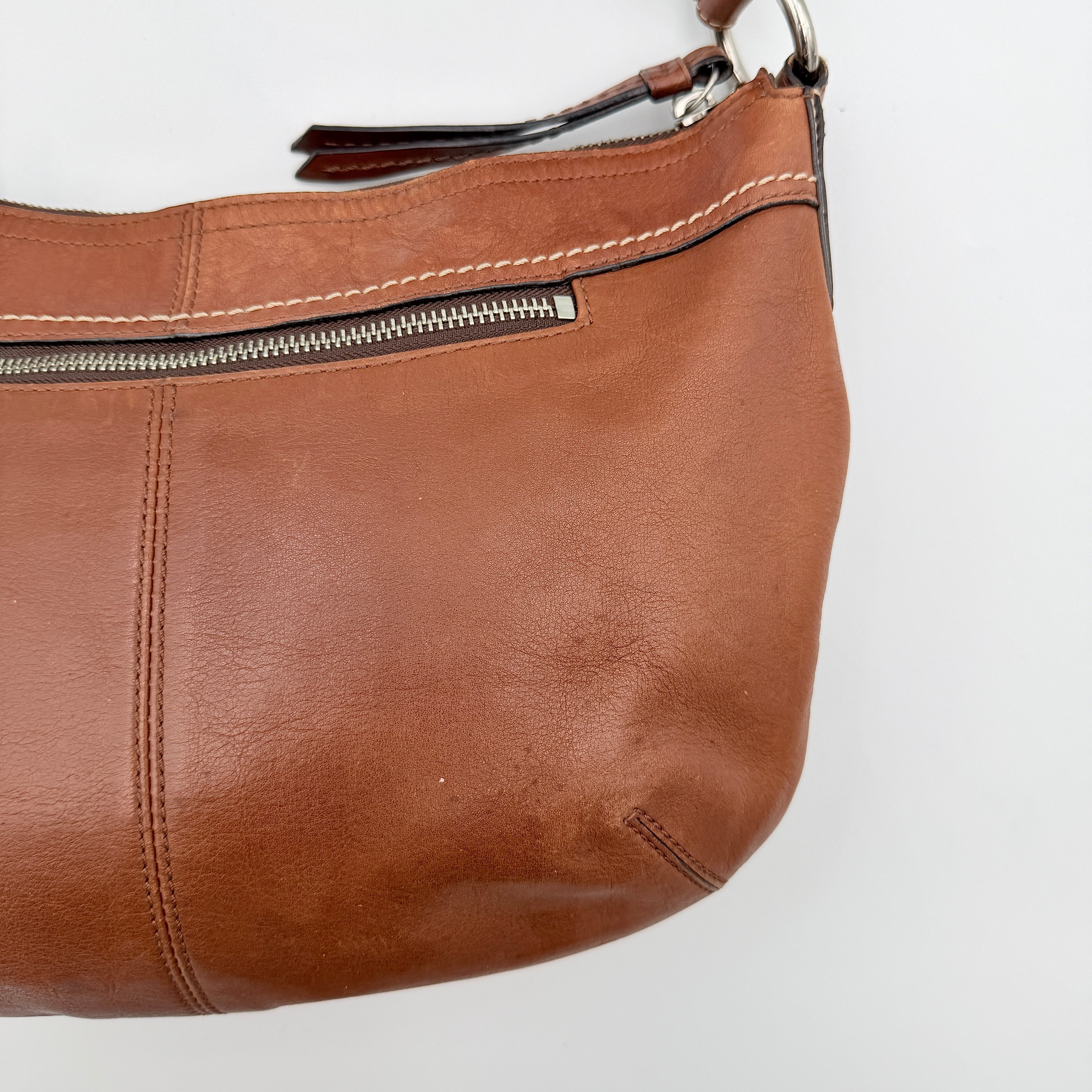 Coach Soho Hobo brown leather shoulder bag with pleated detailing and silver hardware, shown on a white background.