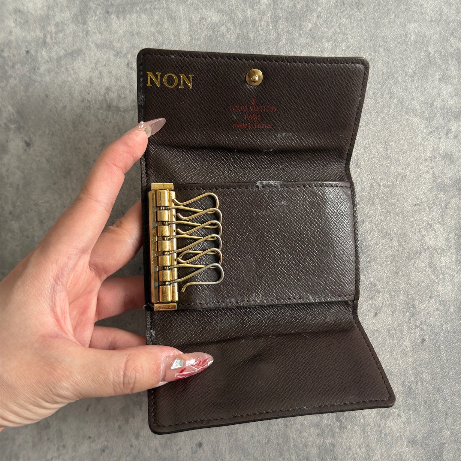 Pre-loved Louis Vuitton Damier Ebene Key Holder with Six Gold-Tone Hooks, Luxury Vintage Designer Accessory with Snap Button Closure.