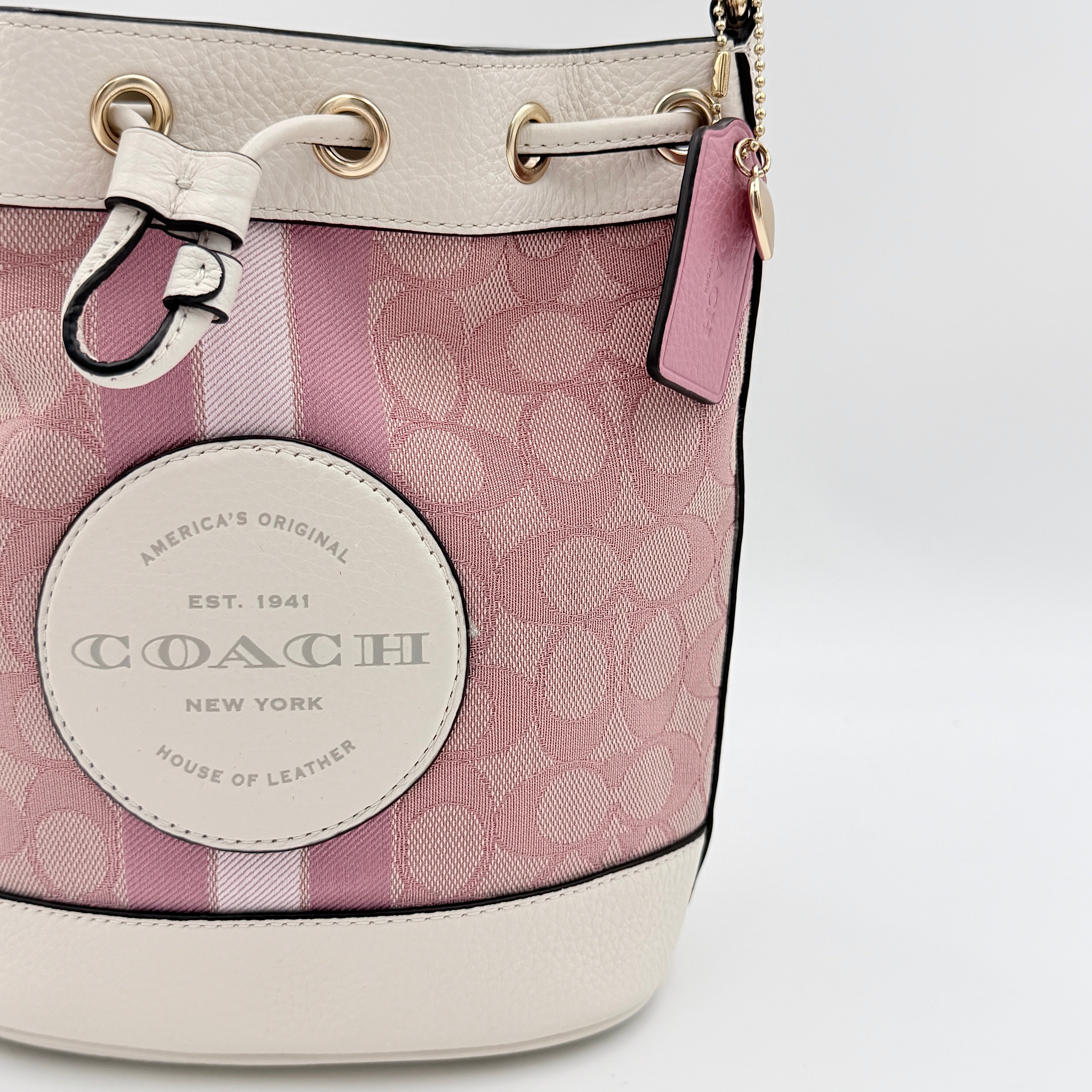 Coach Signature Dempsey 19 bucket bag in pink and white canvas with white leather trim and detachable strap.