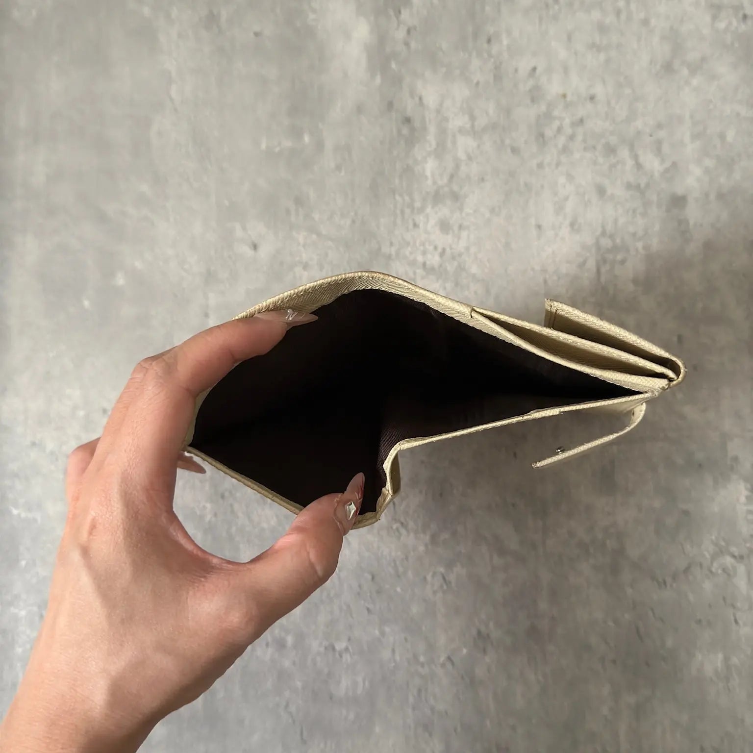 Prada Cream Saffiano Folding Leather Wallet, crafted from textured Saffiano leather with a gold-tone triangular logo and a compact folding design.