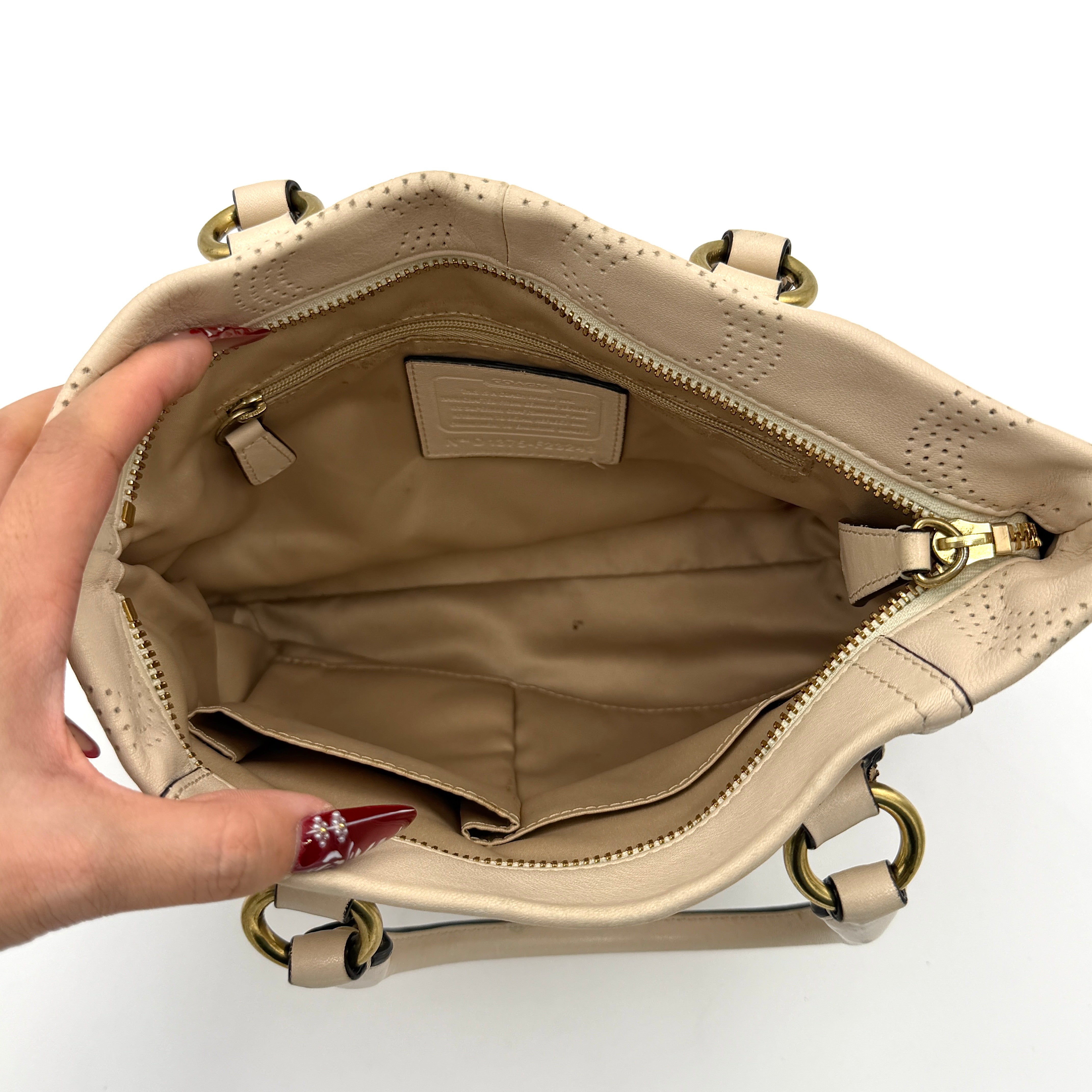 Coach Ashley 2Way cream perforated Op Art leather handbag with dual handles and detachable strap, styled on a white background.