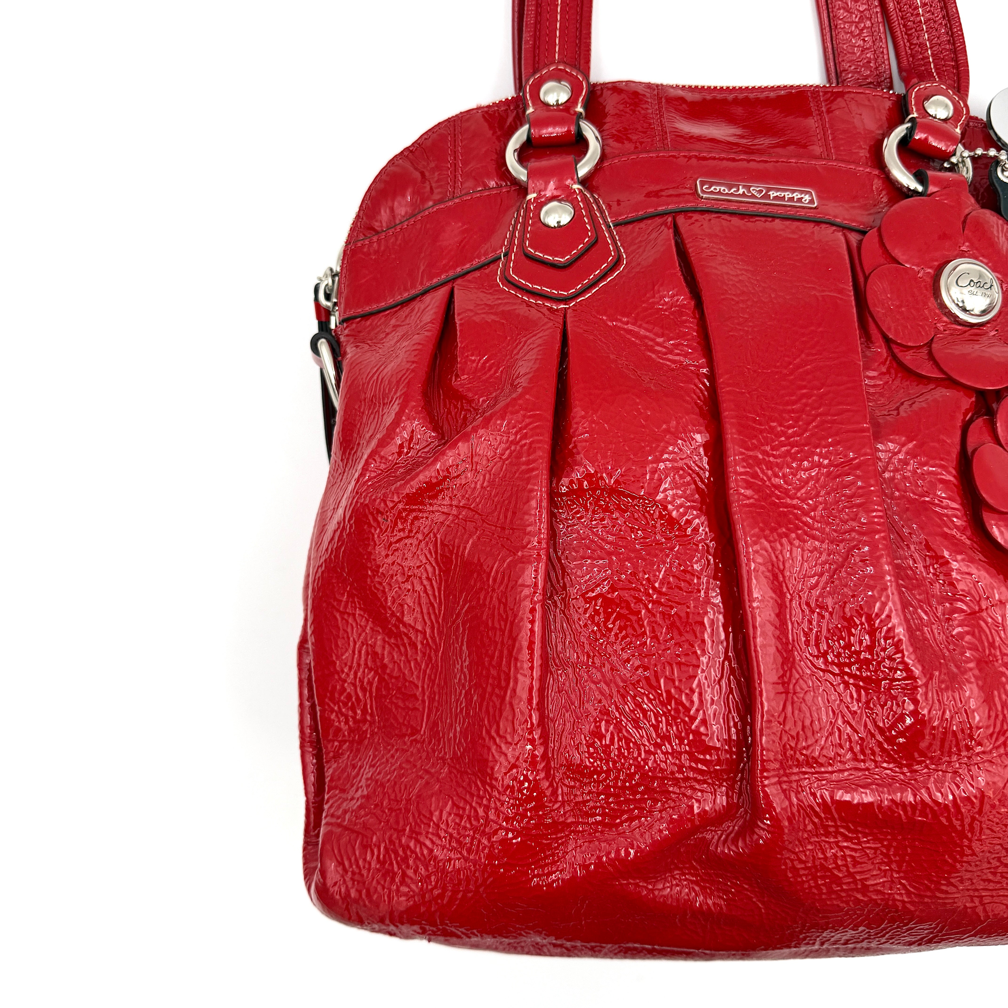 Coach Poppy 2Way shoulder bag in glossy red patent leather with floral appliqué, heart charm, double handles and detachable long strap.