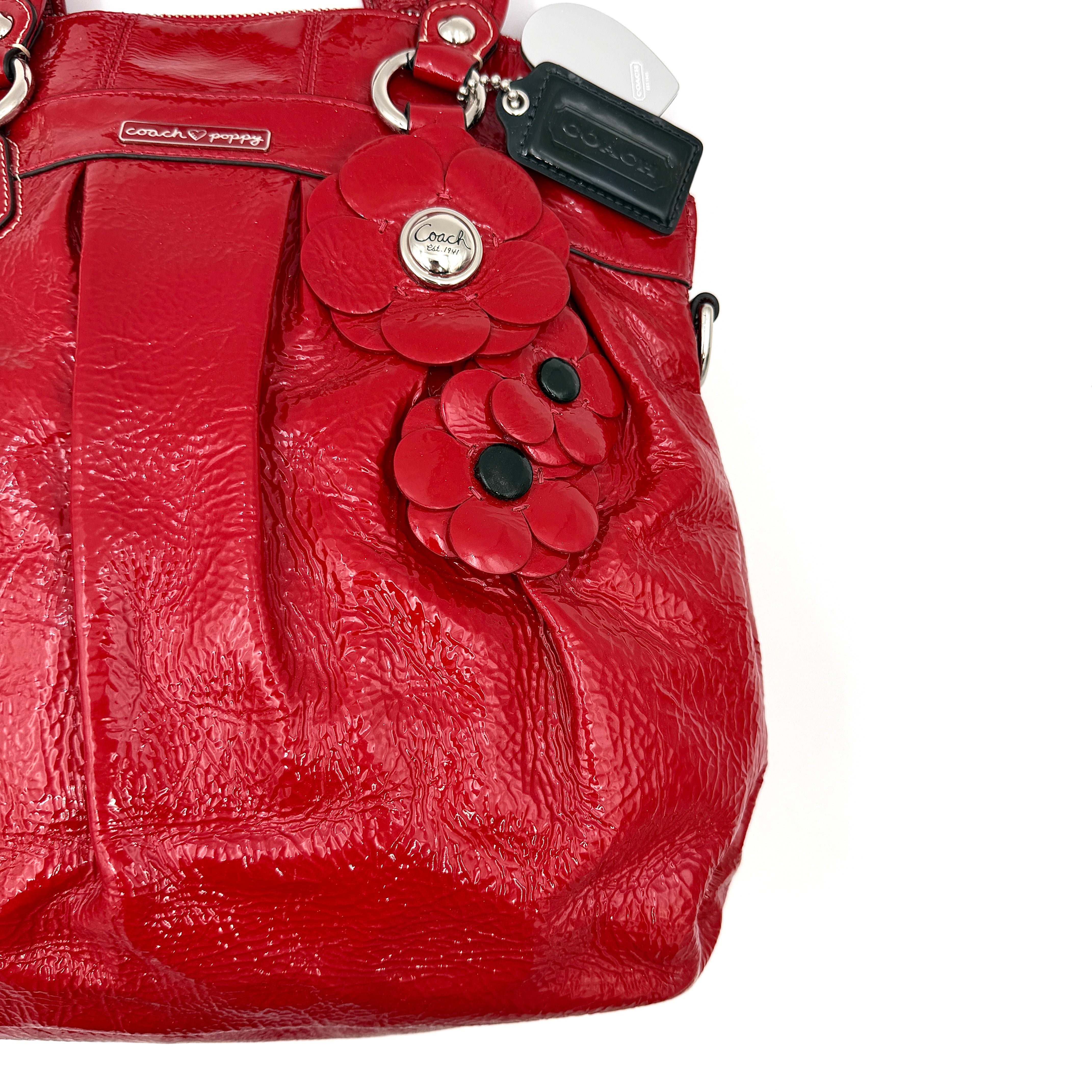 Coach Poppy 2Way shoulder bag in glossy red patent leather with floral appliqué, heart charm, double handles and detachable long strap.