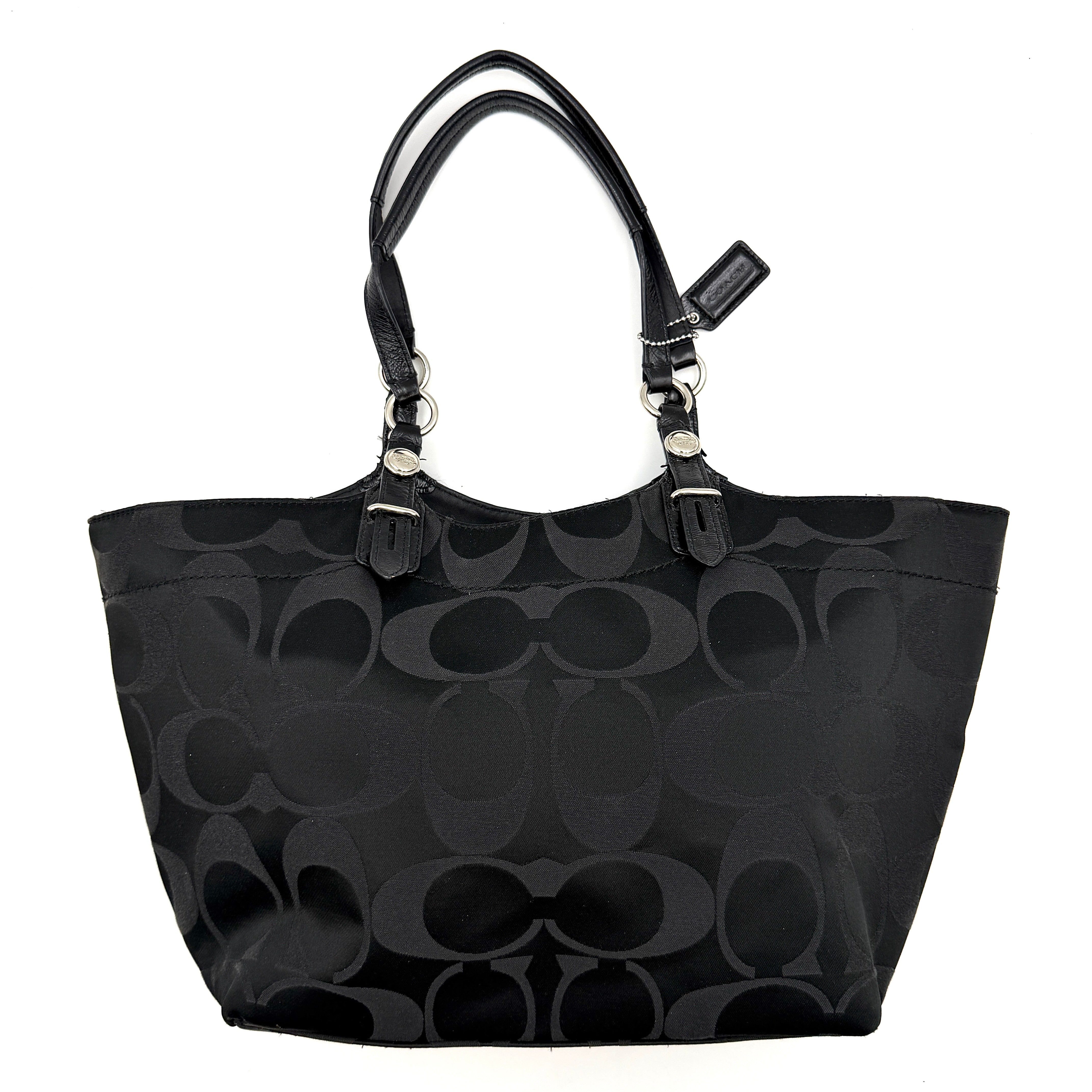 Coach black signature canvas tote with leather handles and silver hardware, set against a white background.
