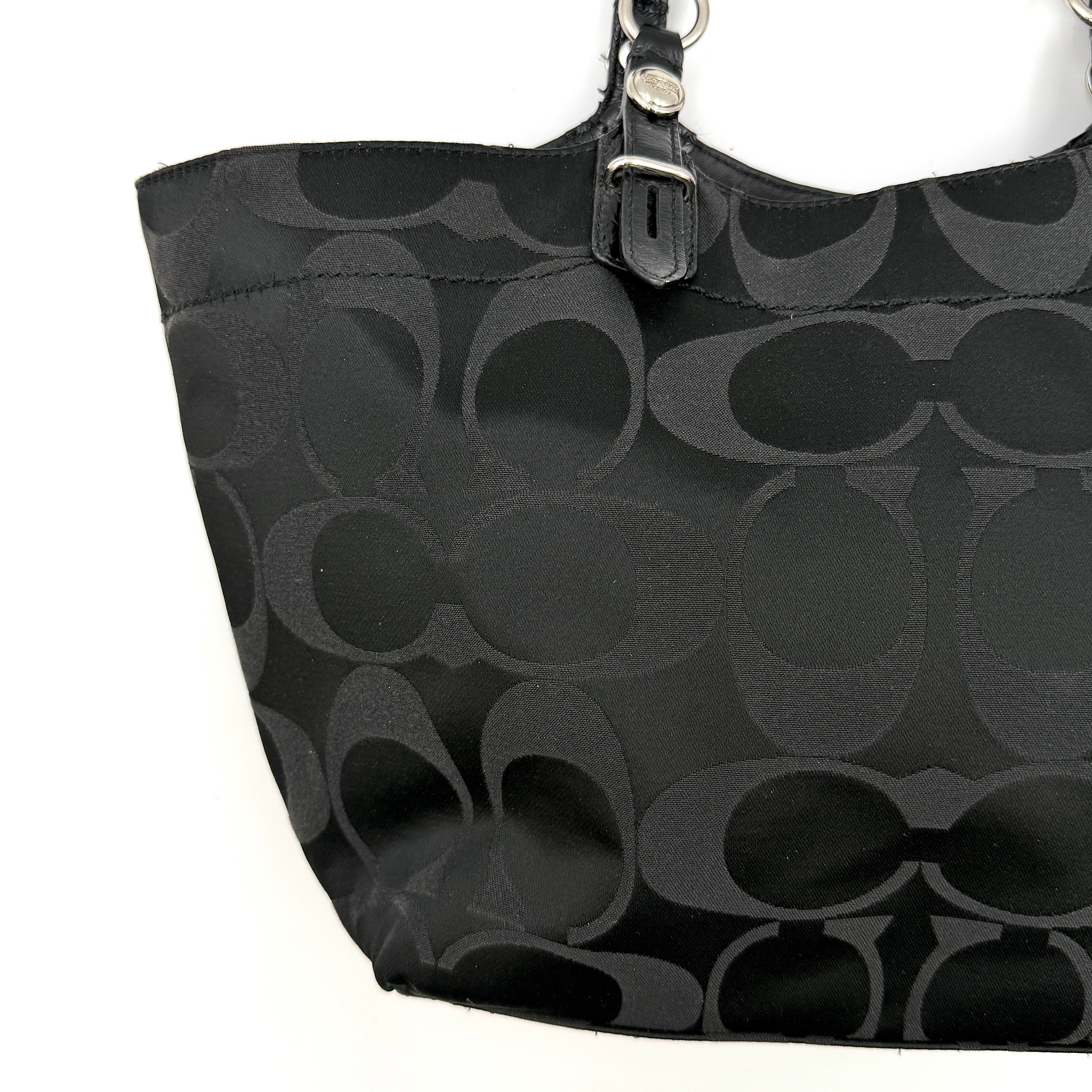 Coach black signature canvas tote with leather handles and silver hardware, set against a white background.