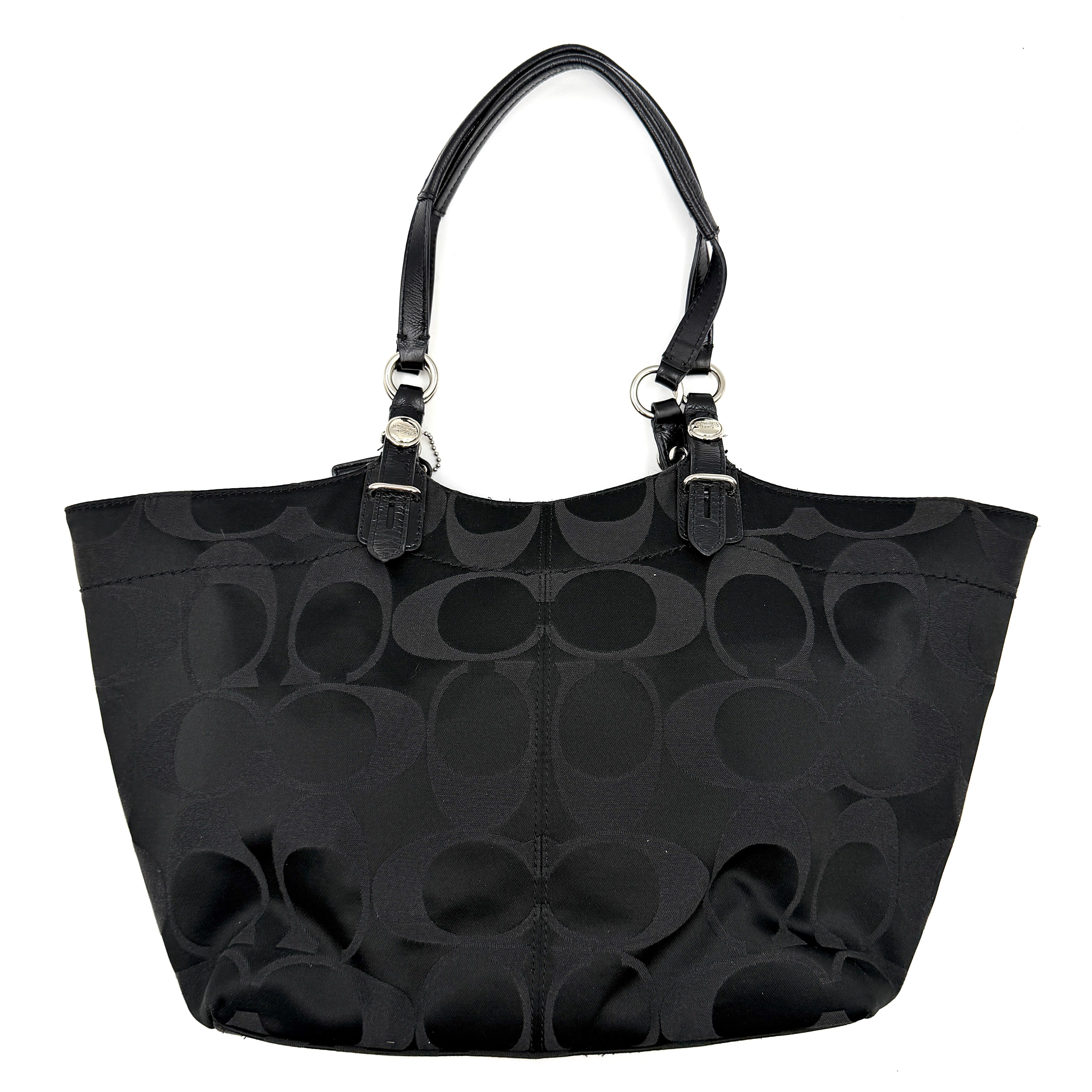 Coach black signature canvas tote with leather handles and silver hardware, set against a white background.