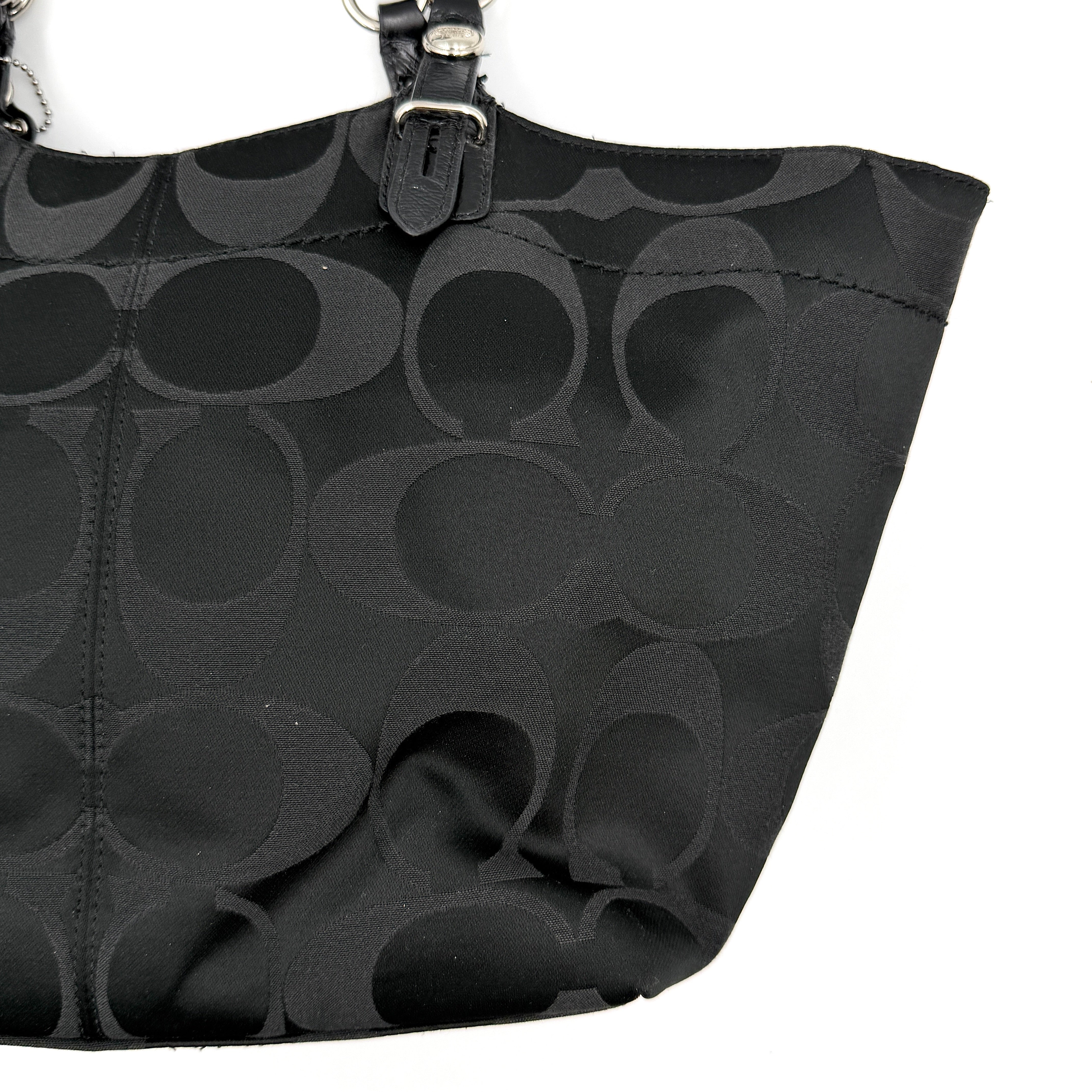 Coach black signature canvas tote with leather handles and silver hardware, set against a white background.