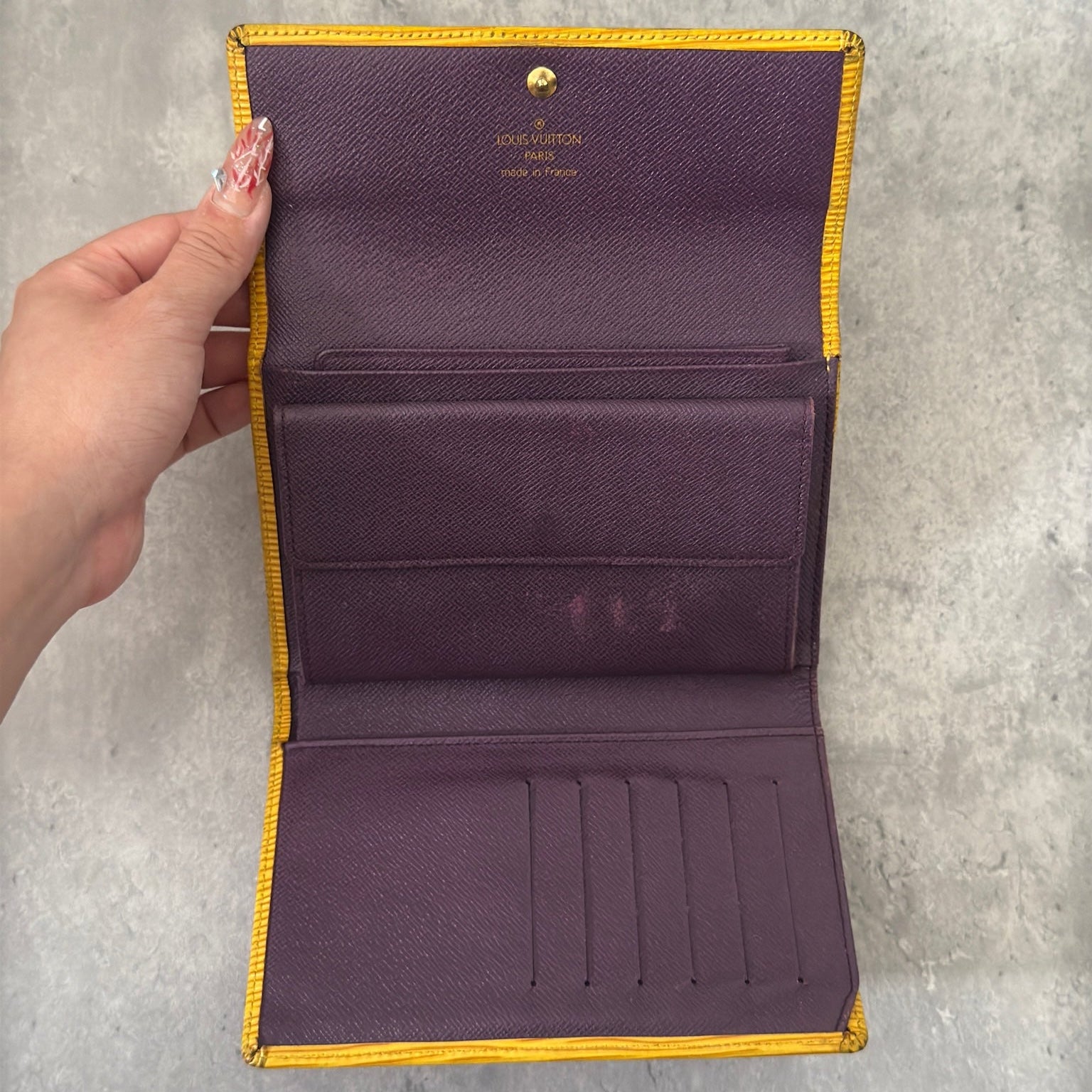 Louis Vuitton Epi leather wallet in yellow with purple leather interior, showcasing multiple card slots and a spacious bill compartment, a blend of functionality and luxury.