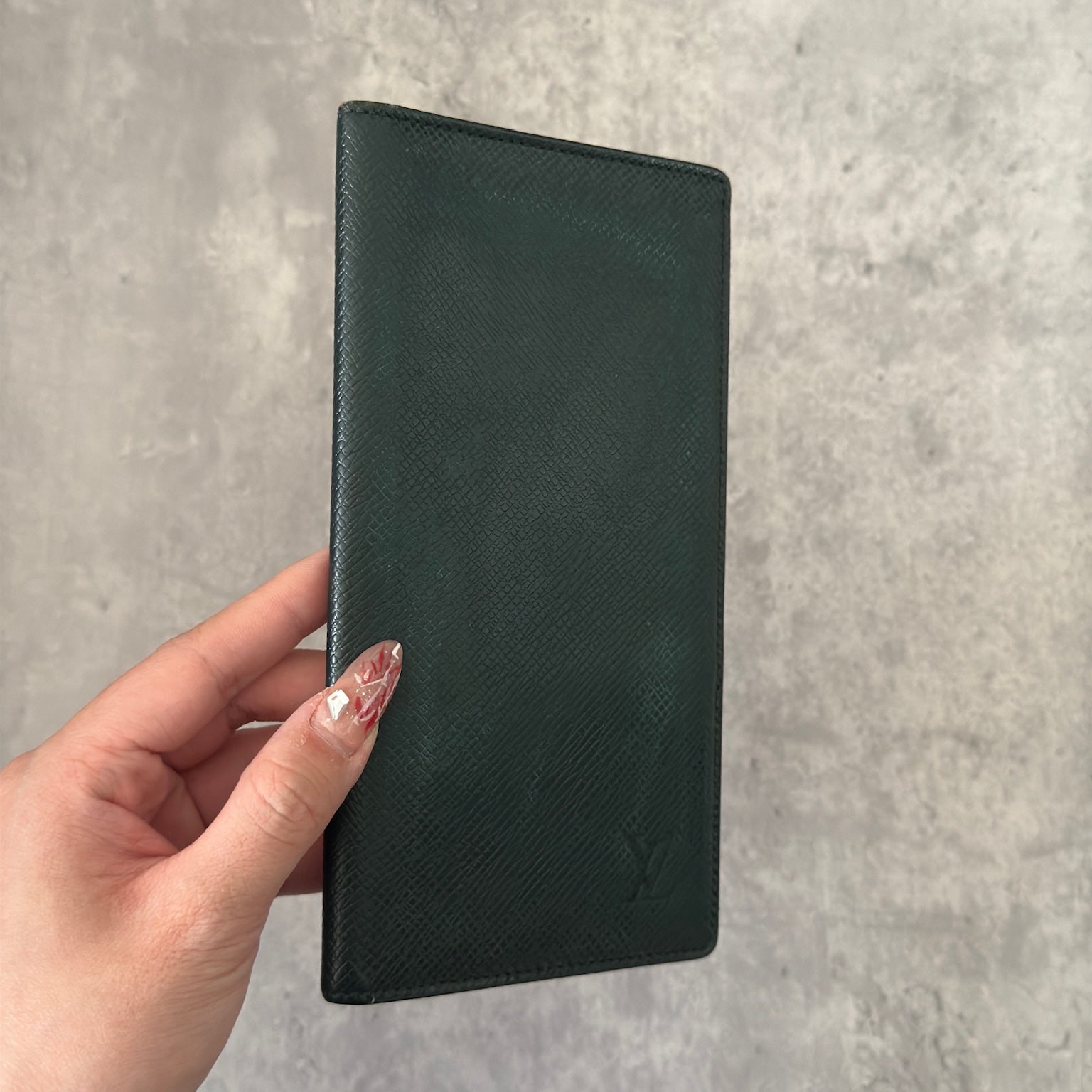 Louis Vuitton Taiga Porte-Valeurs long wallet in green, showcasing the embossed LV logo and a structured interior with multiple card slots and compartments, embodying luxury and organization.