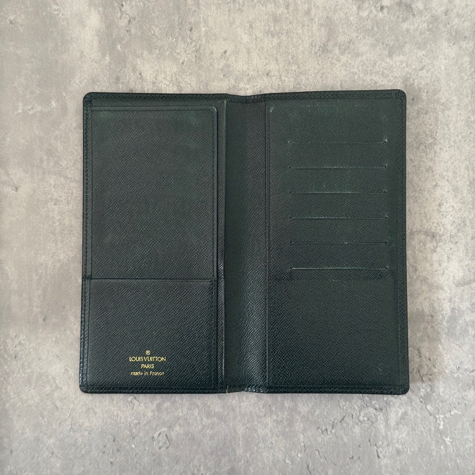 Louis Vuitton Taiga Porte-Valeurs long wallet in green, showcasing the embossed LV logo and a structured interior with multiple card slots and compartments, embodying luxury and organization.