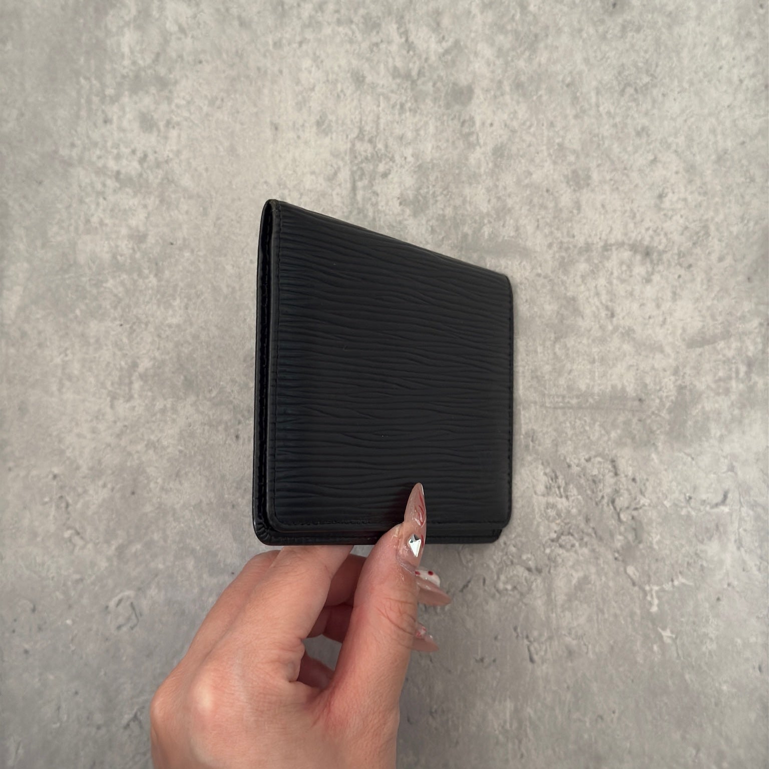 Luxurious black leather Louis Vuitton vintage card, ID, and passport holder featuring embossed logo, designed for sophisticated organization and style.