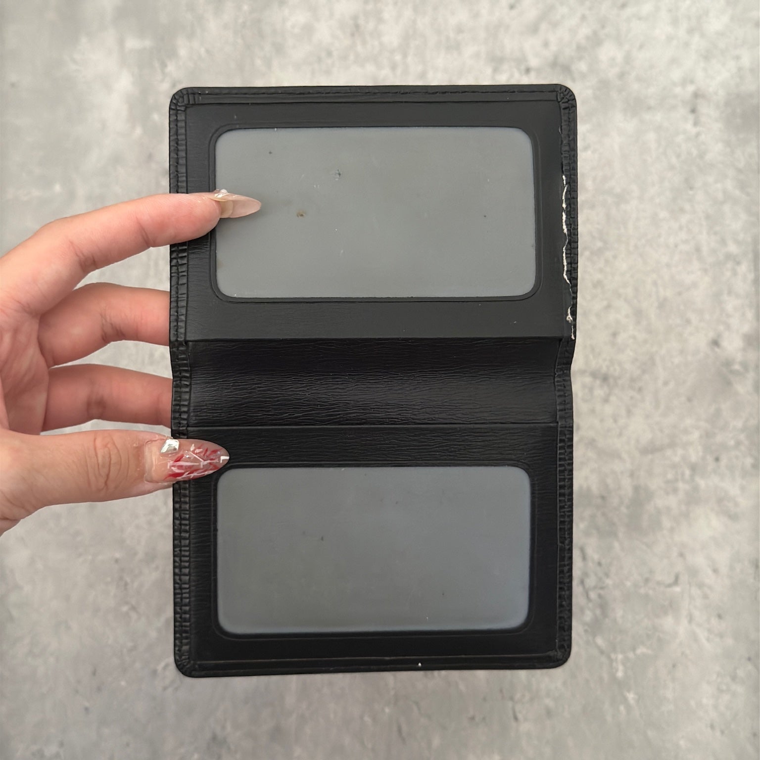 Luxurious black leather Louis Vuitton vintage card, ID, and passport holder featuring embossed logo, designed for sophisticated organization and style.