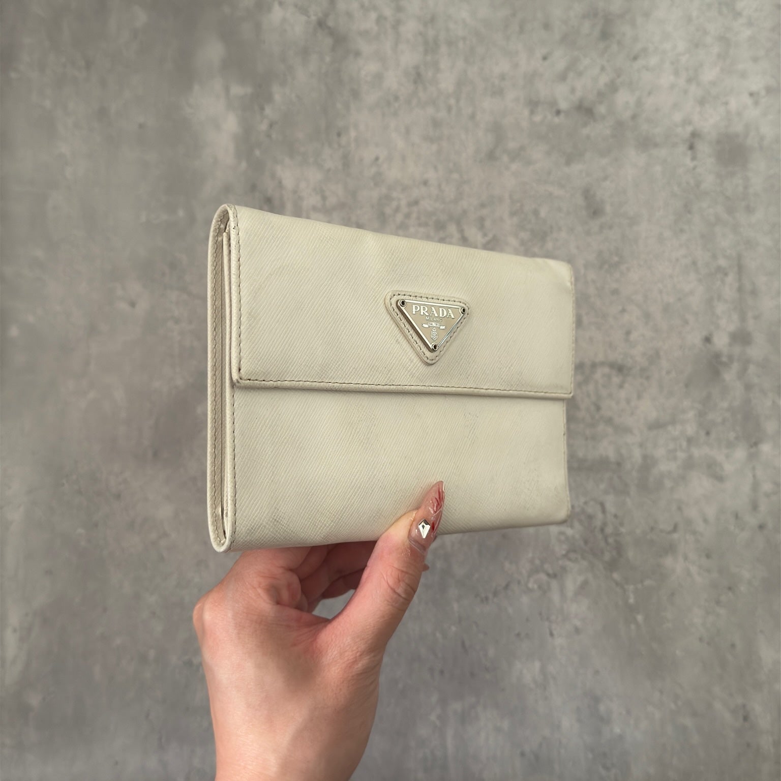 Pre-loved Prada Tessuto Nero leather trifold wallet with triangle logo plate in off-white, featuring card slots and a snap closure.
