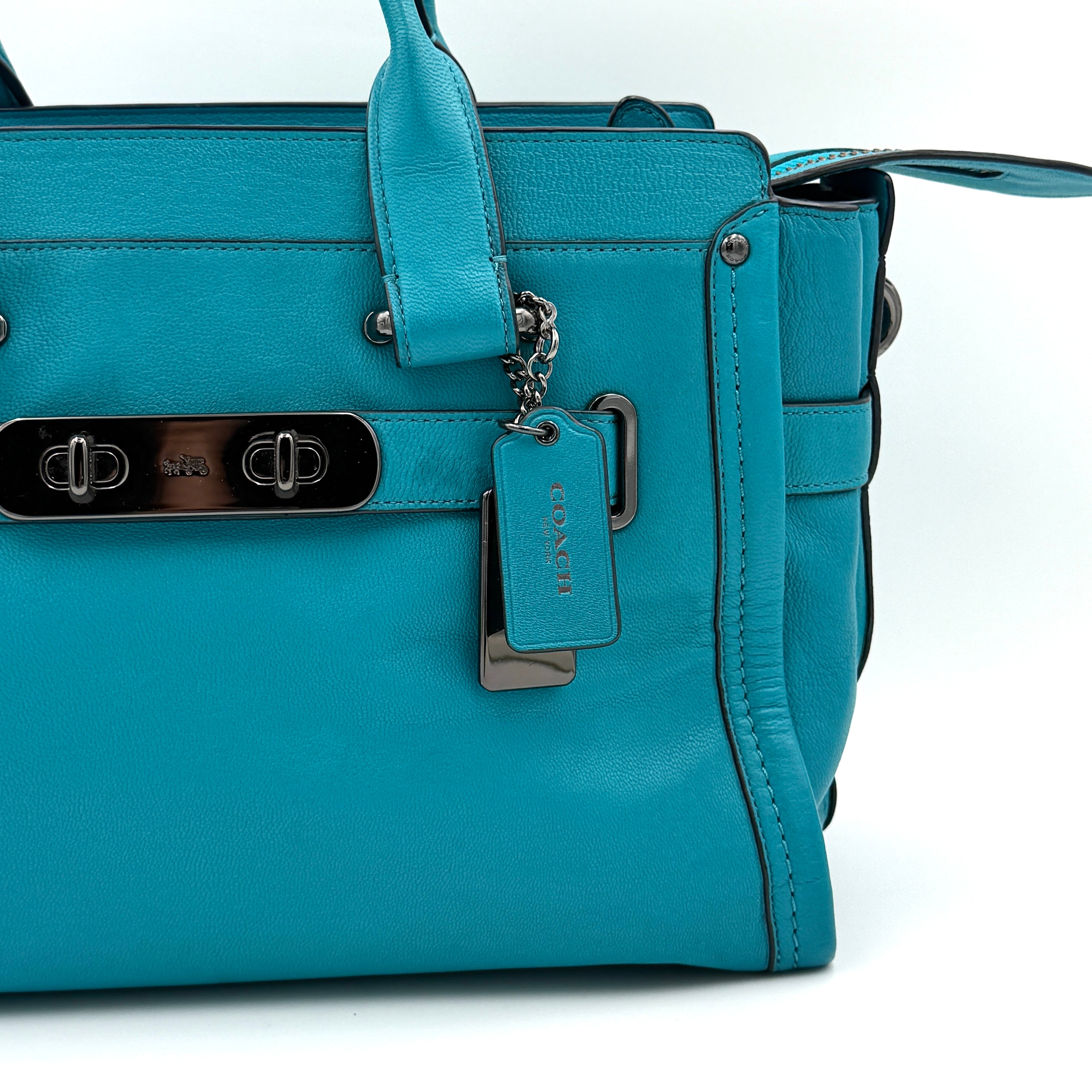 Coach Swagger 27 Carryall in vivid turquoise leather with double top handles, gunmetal hardware, and detachable strap.