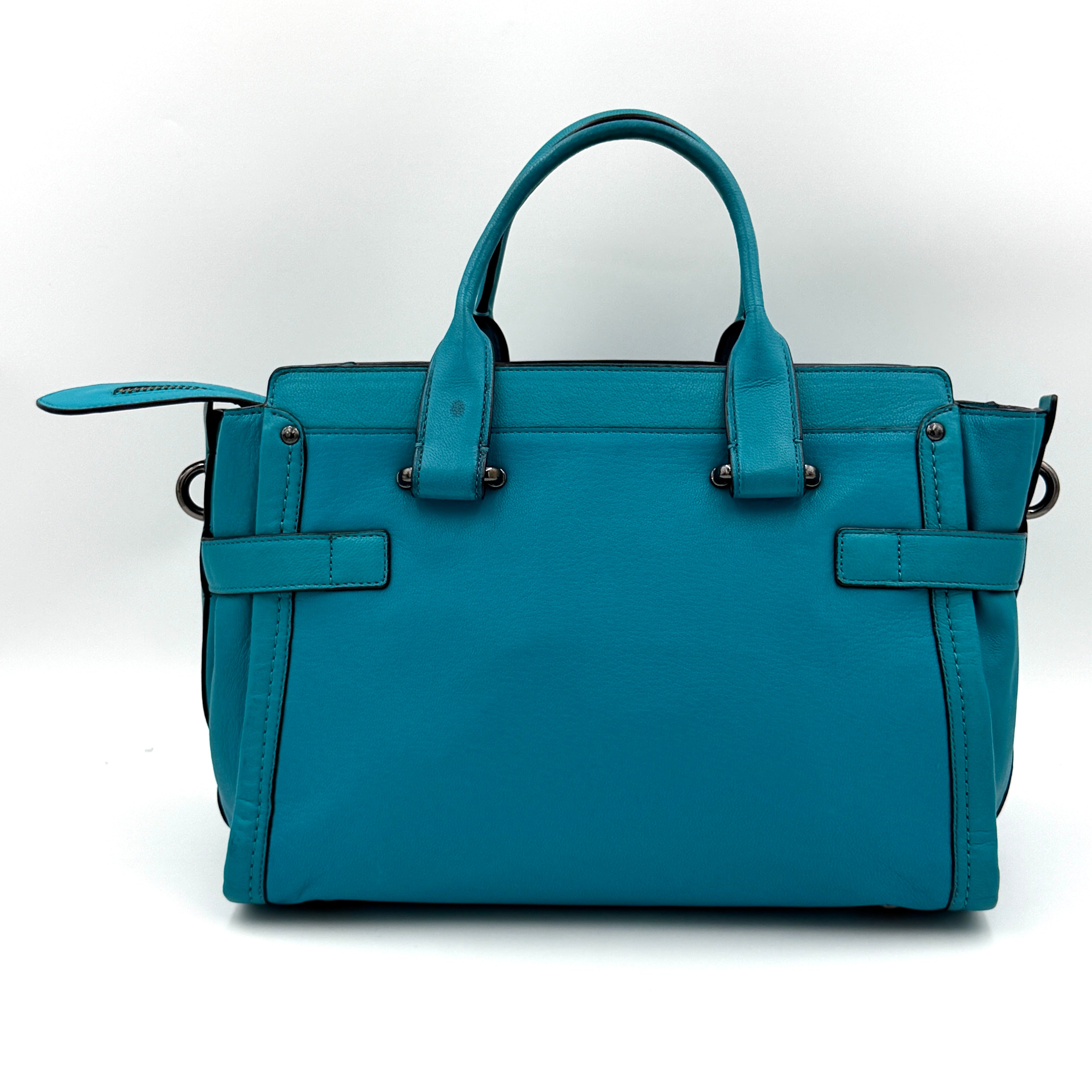 Coach Swagger 27 Carryall in vivid turquoise leather with double top handles, gunmetal hardware, and detachable strap.