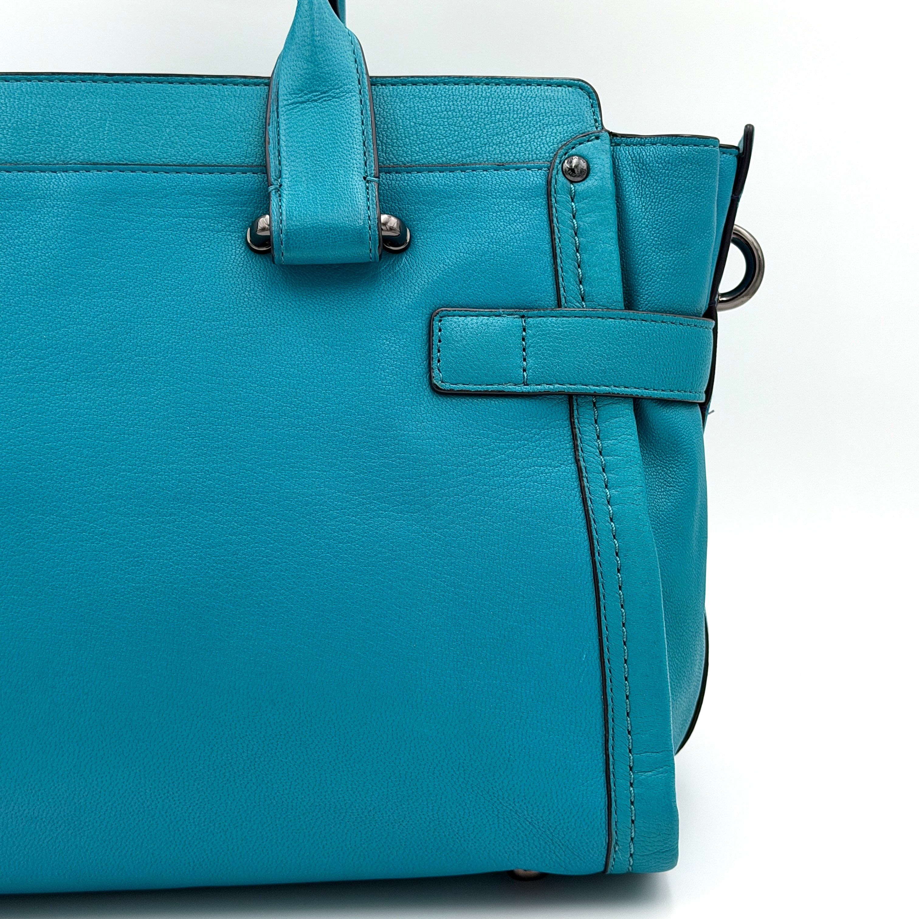 Coach Swagger 27 Carryall in vivid turquoise leather with double top handles, gunmetal hardware, and detachable strap.
