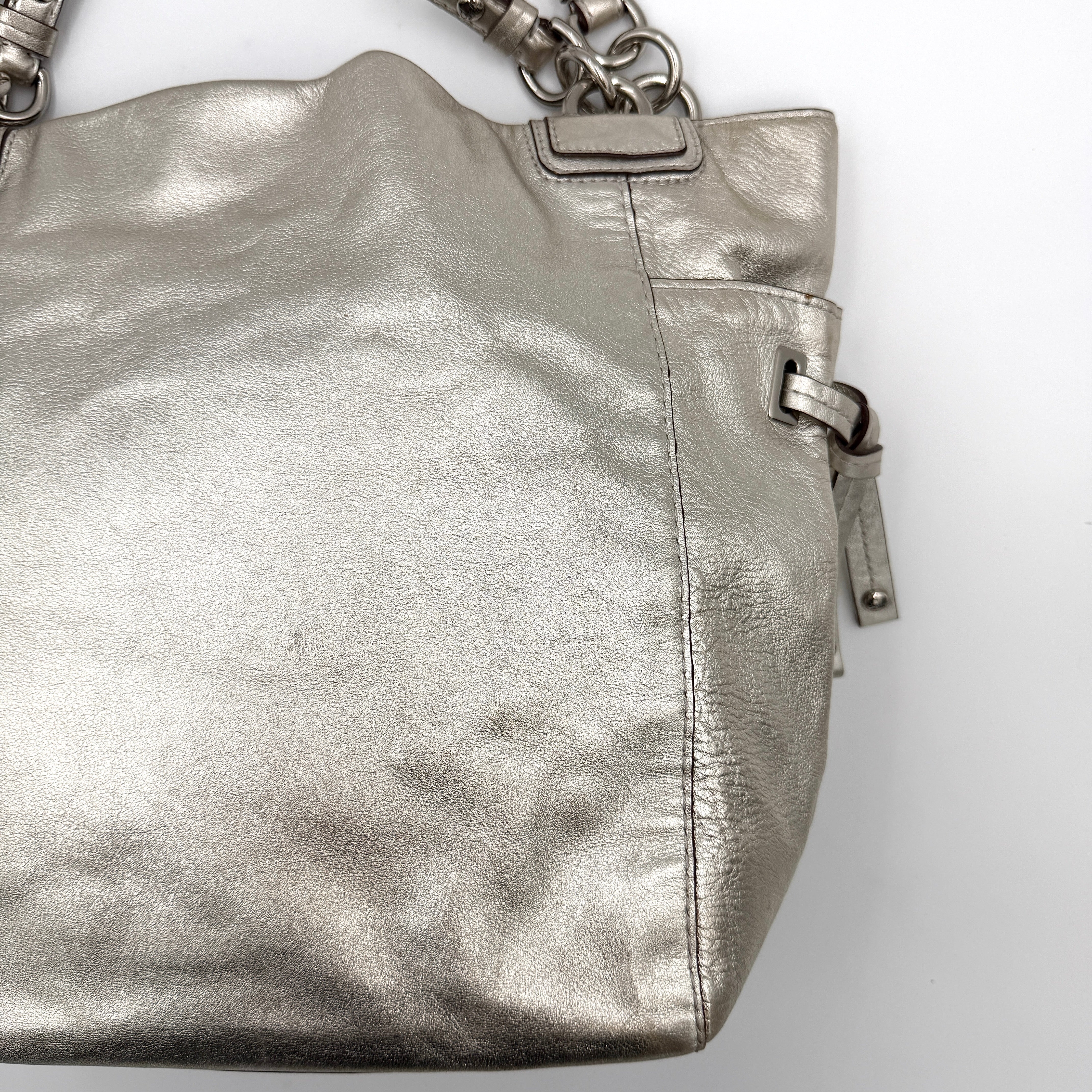 Coach Peyton Metallic Shoulder Bag in shimmering silver leather with dual top handles and polished hardware.