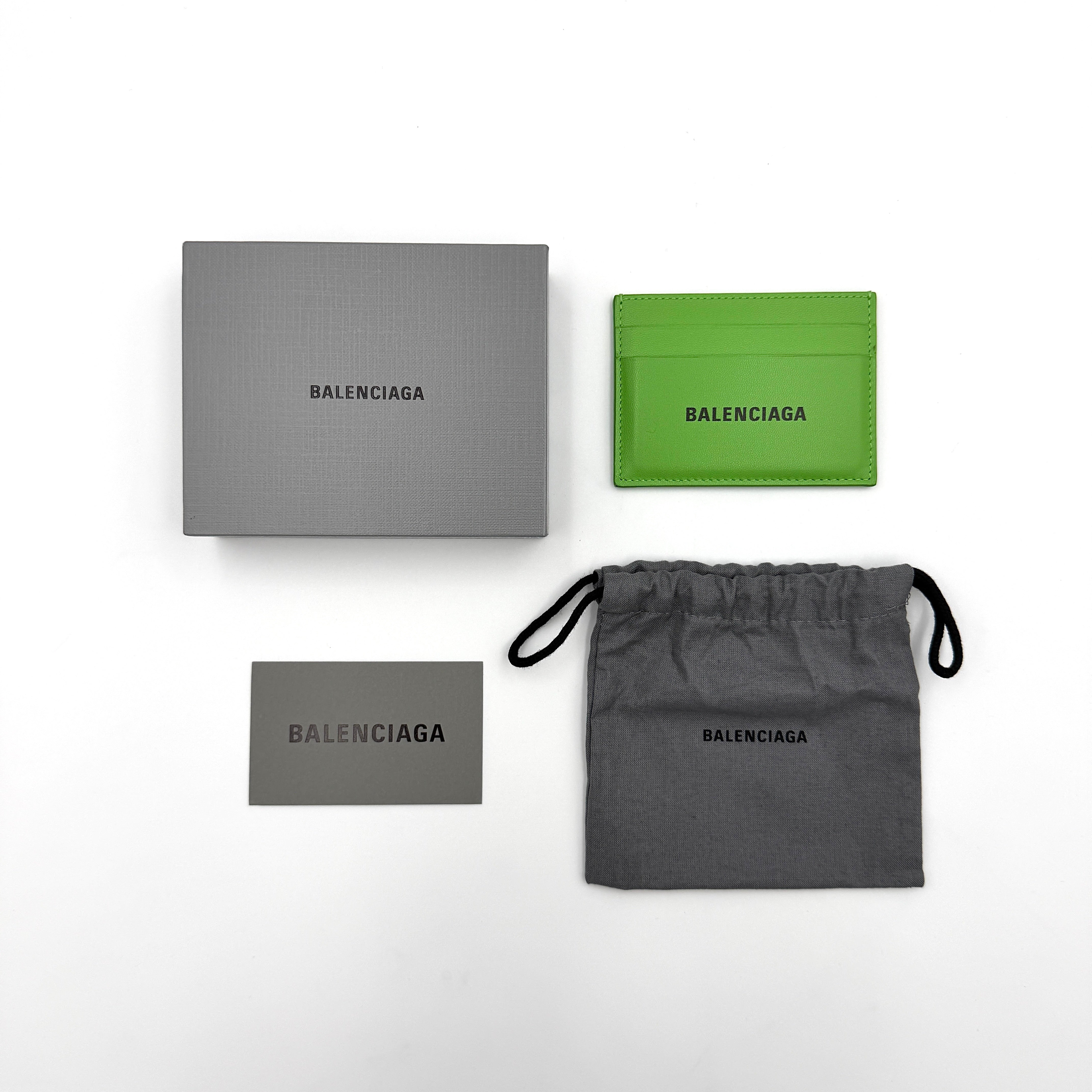A vivid green Balenciaga leather cardholder featuring a bold black logo and minimalist silhouette.