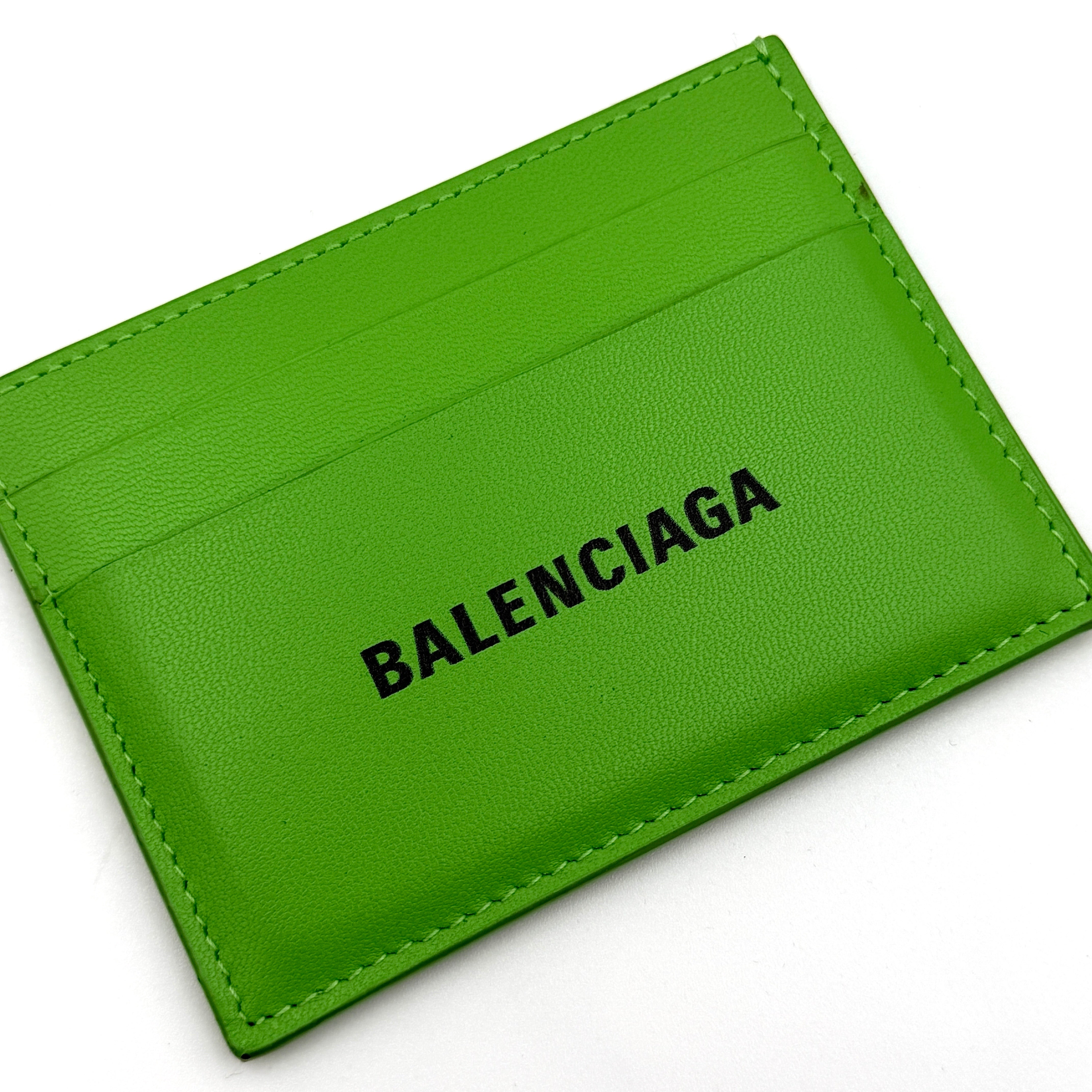 A vivid green Balenciaga leather cardholder featuring a bold black logo and minimalist silhouette.
