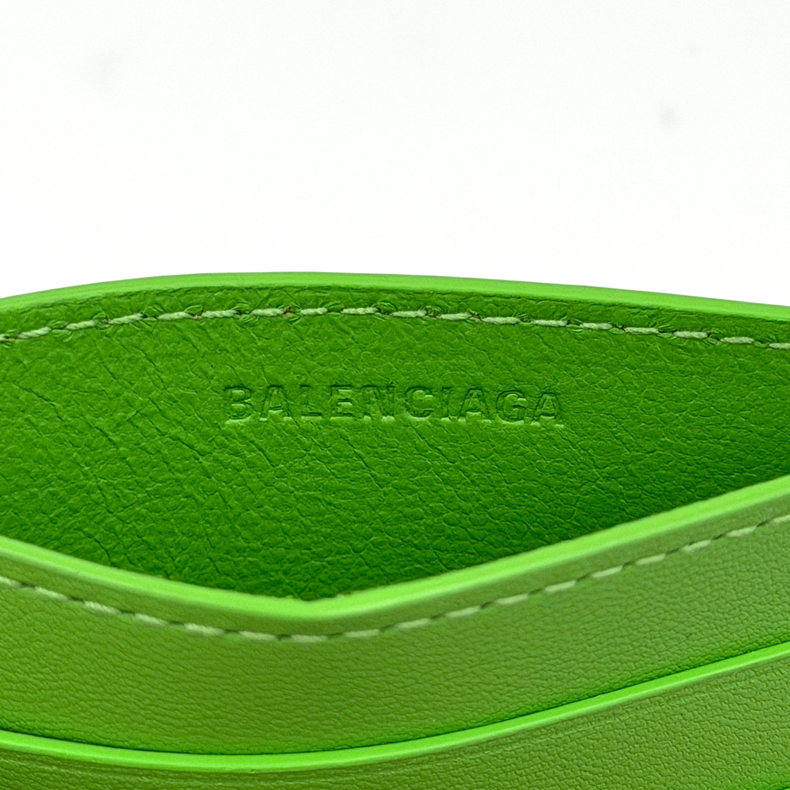 A vivid green Balenciaga leather cardholder featuring a bold black logo and minimalist silhouette.