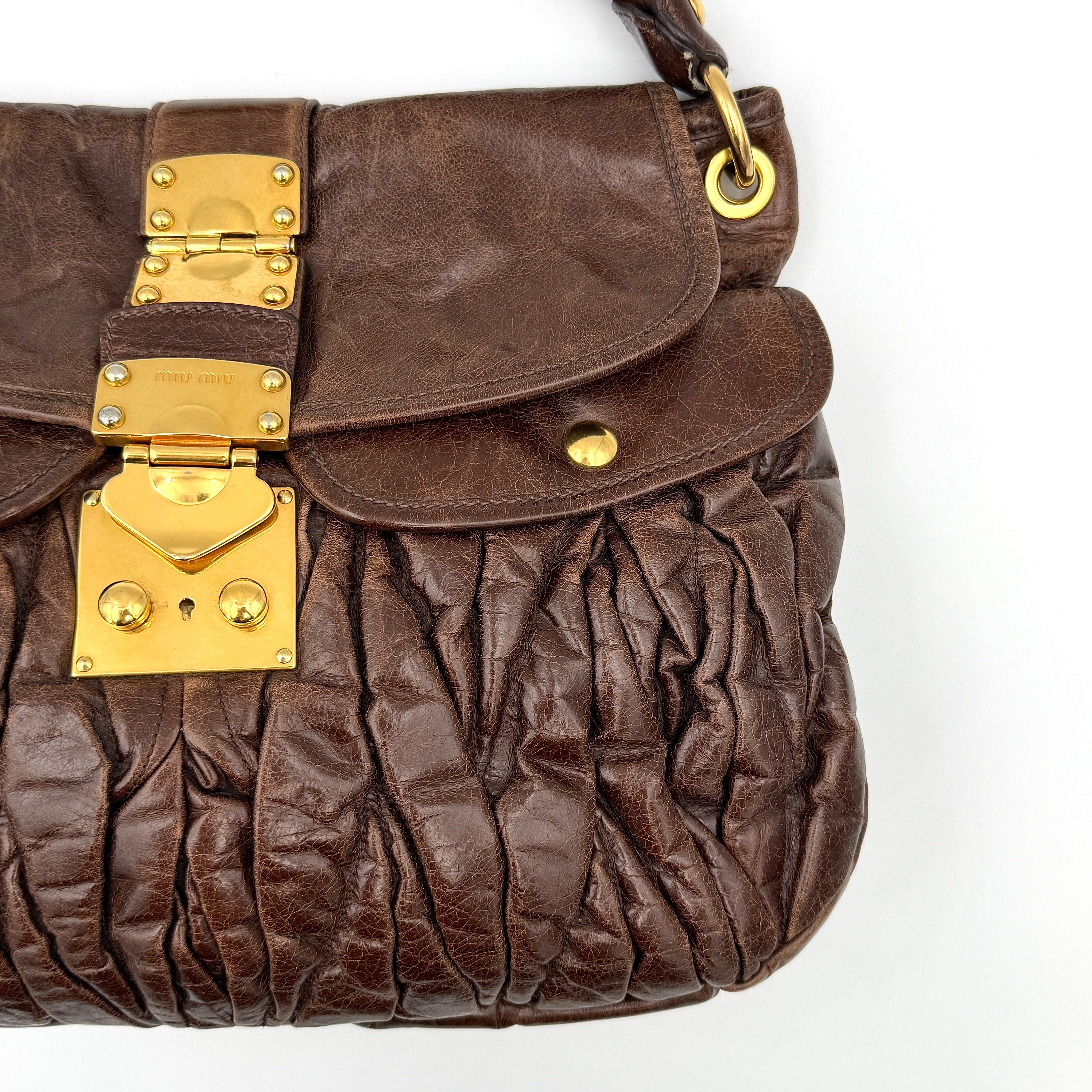 Miu Miu Coffer Hobo bag in deep brown matelassé leather with braided handle, gold hardware, and detachable strap.