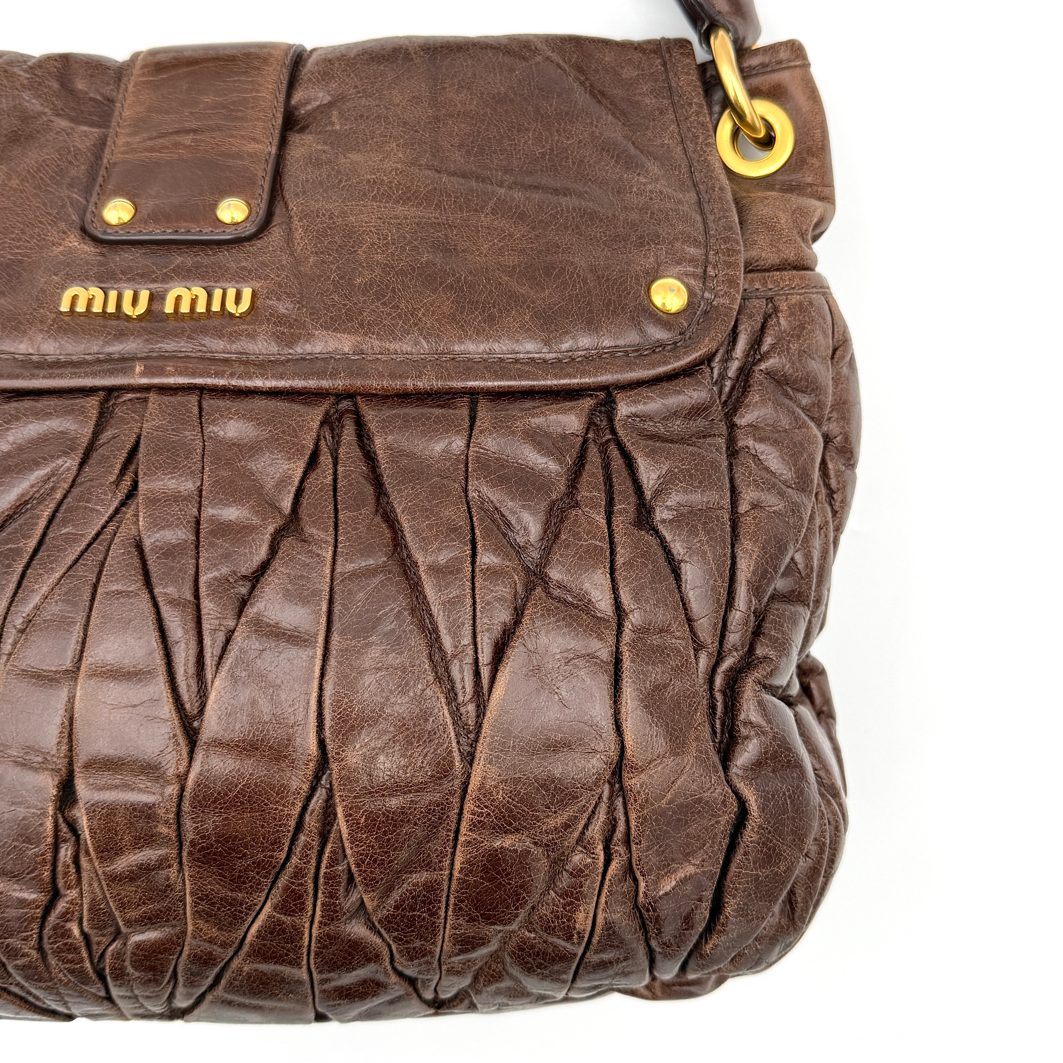 Miu Miu Coffer Hobo bag in deep brown matelassé leather with braided handle, gold hardware, and detachable strap.