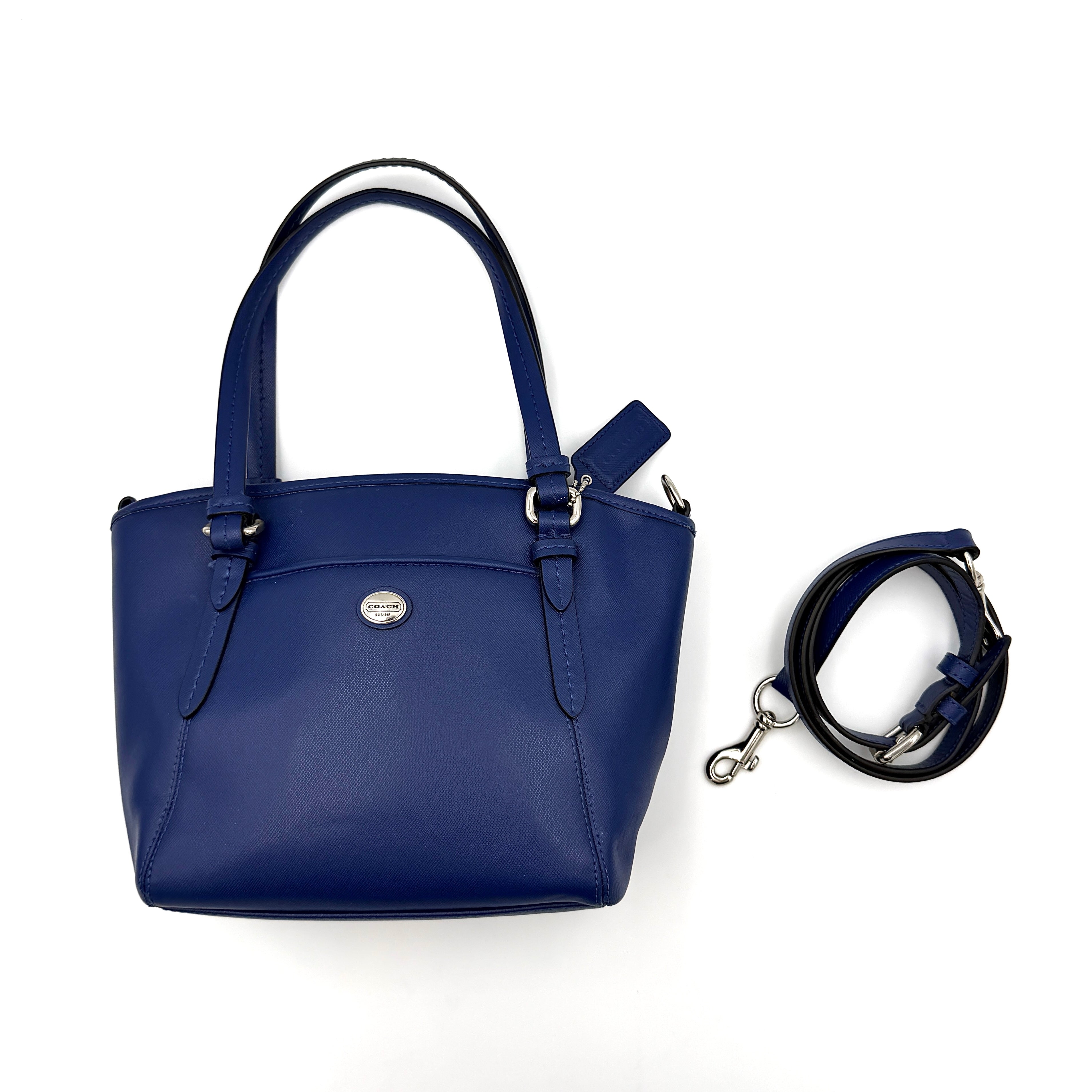 A structured cobalt blue Coach tote bag with silver hardware, dual handles, and an optional crossbody strap, displayed against a clean background.