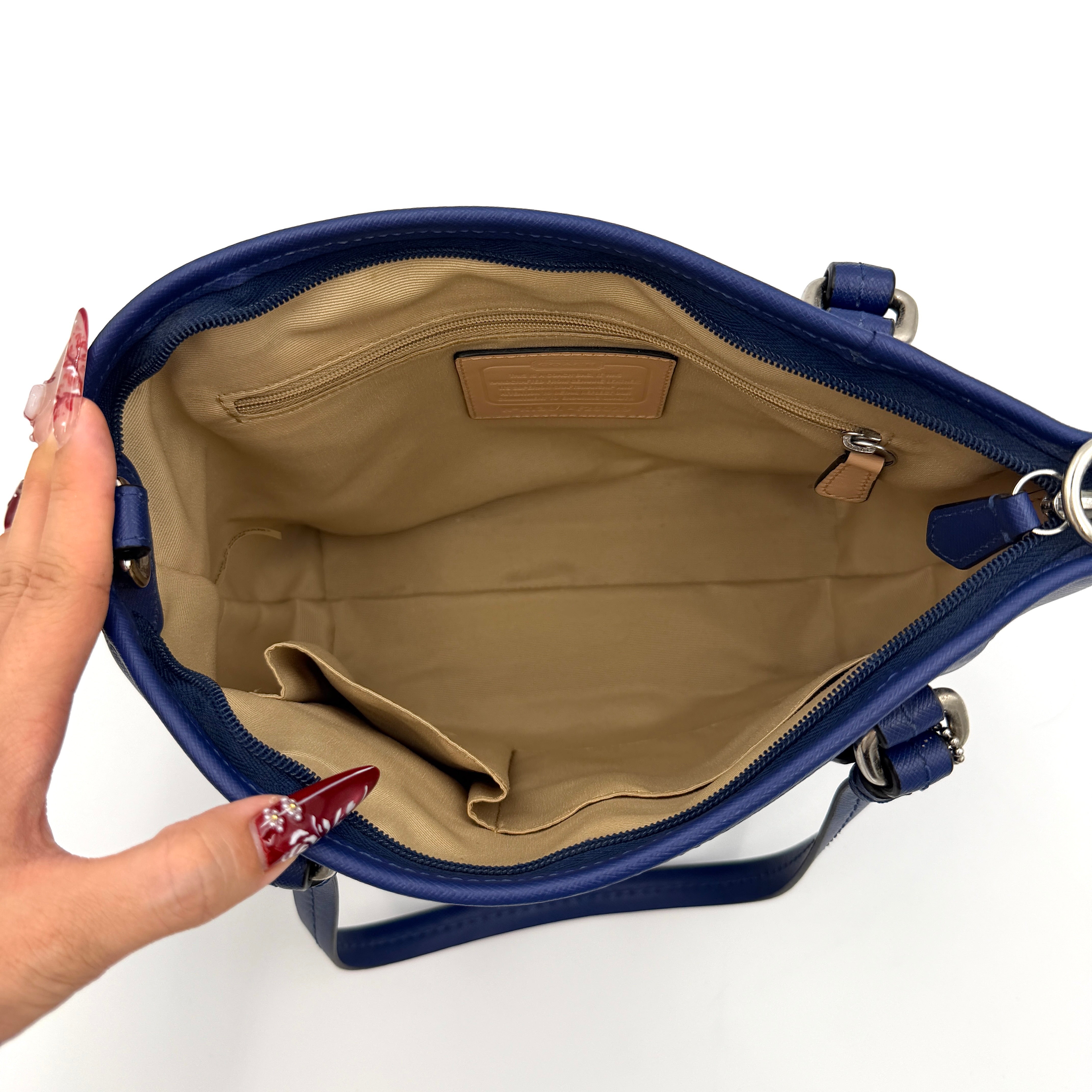 A structured cobalt blue Coach tote bag with silver hardware, dual handles, and an optional crossbody strap, displayed against a clean background.