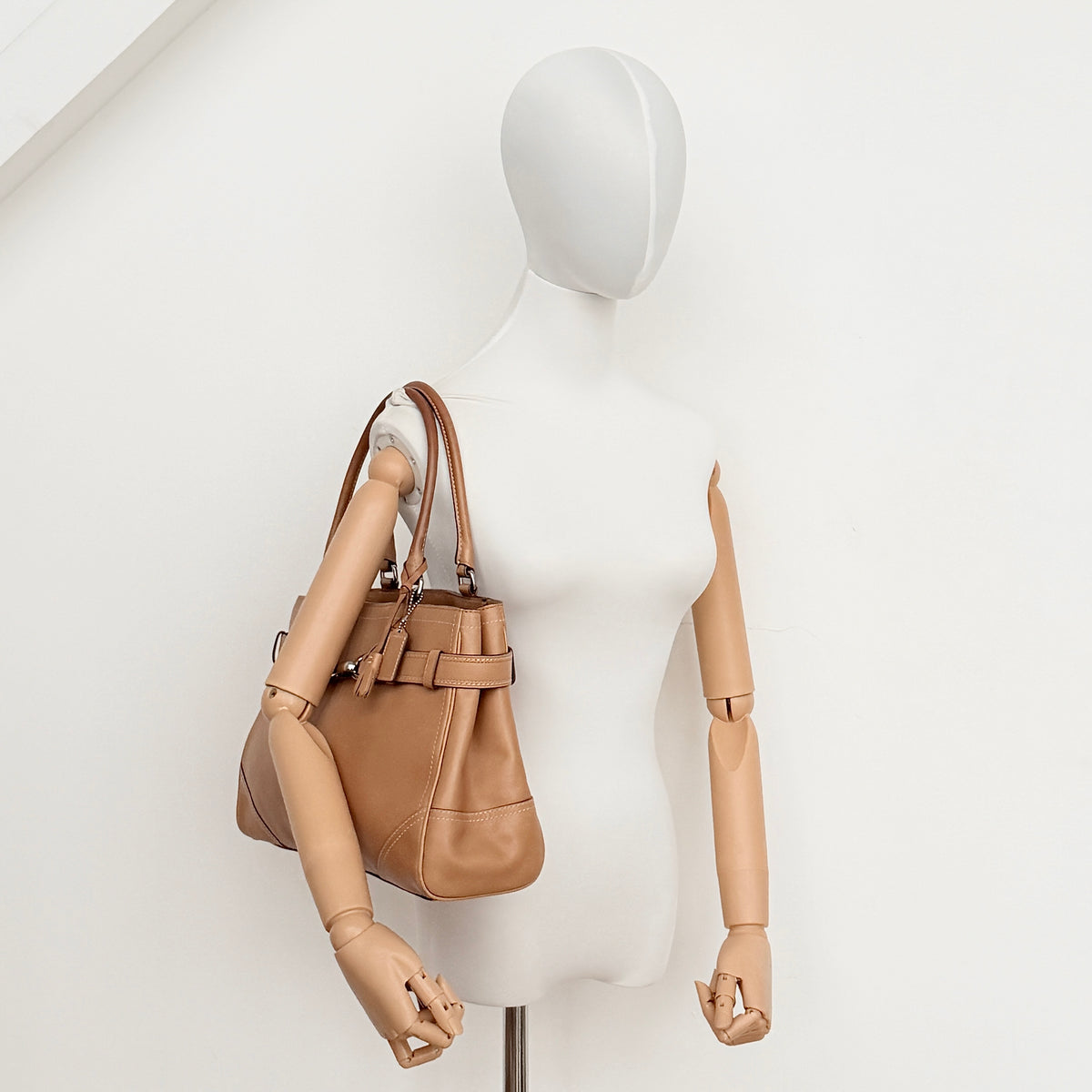 Coach Hampton Carryall in caramel brown leather with silver hardware and double handles, photographed against a white backdrop.