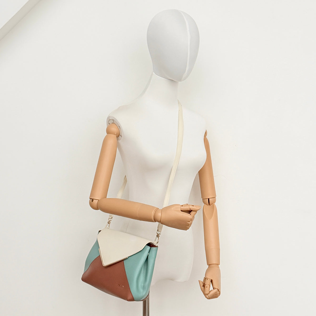 Furla Kelis crossbody bag in brown, blue, and cream leather with envelope flap and gold-tone hardware, displayed on a Furla dust bag.