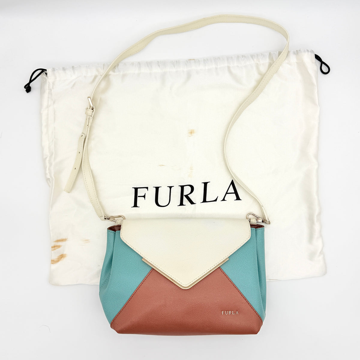 Furla Kelis crossbody bag in brown, blue, and cream leather with envelope flap and gold-tone hardware, displayed on a Furla dust bag.