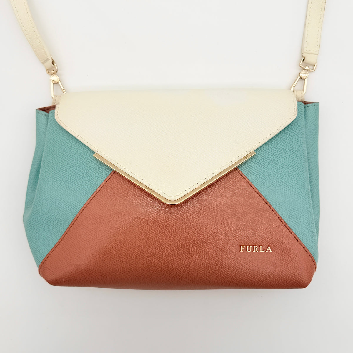 Furla Kelis crossbody bag in brown, blue, and cream leather with envelope flap and gold-tone hardware, displayed on a Furla dust bag.