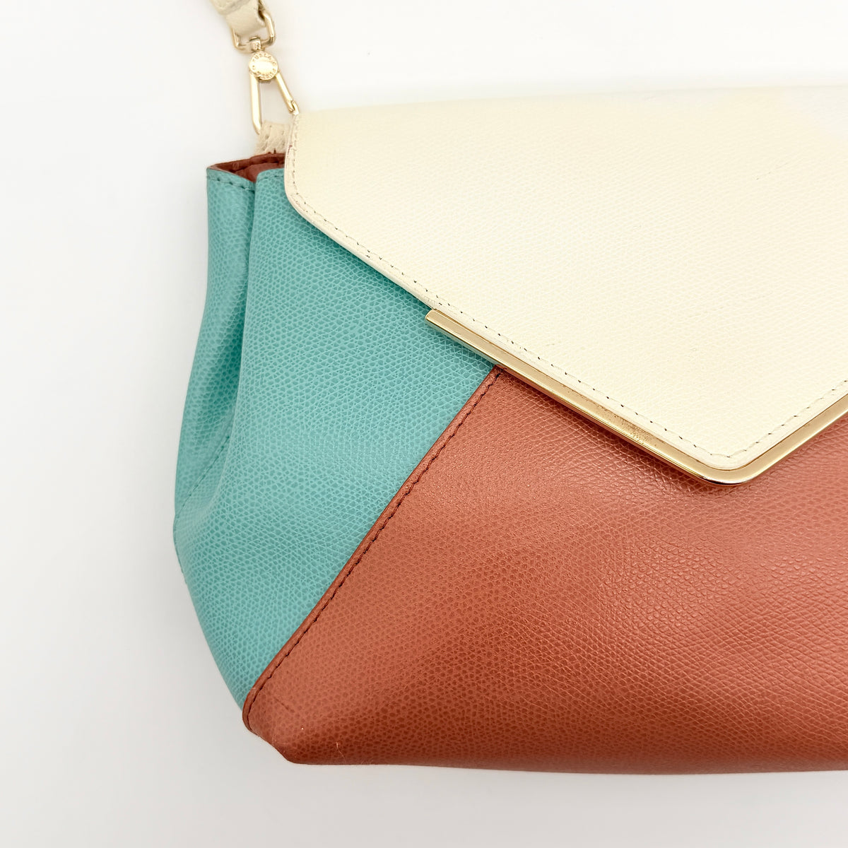 Furla Kelis crossbody bag in brown, blue, and cream leather with envelope flap and gold-tone hardware, displayed on a Furla dust bag.