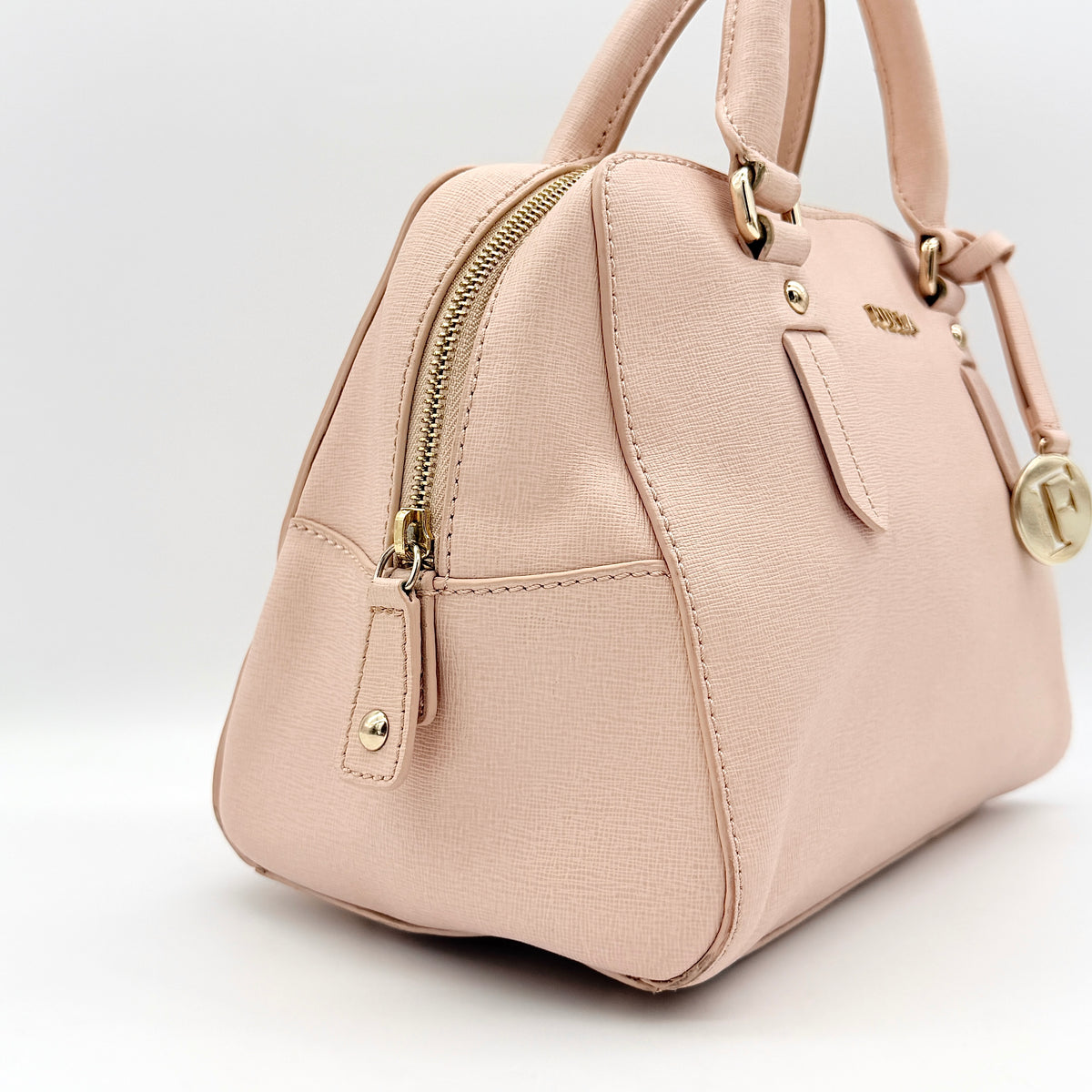 Furla Elena 2Way Saffiano leather satchel in beige with gold-tone hardware and removable strap, displayed on Furla-branded dust bag.