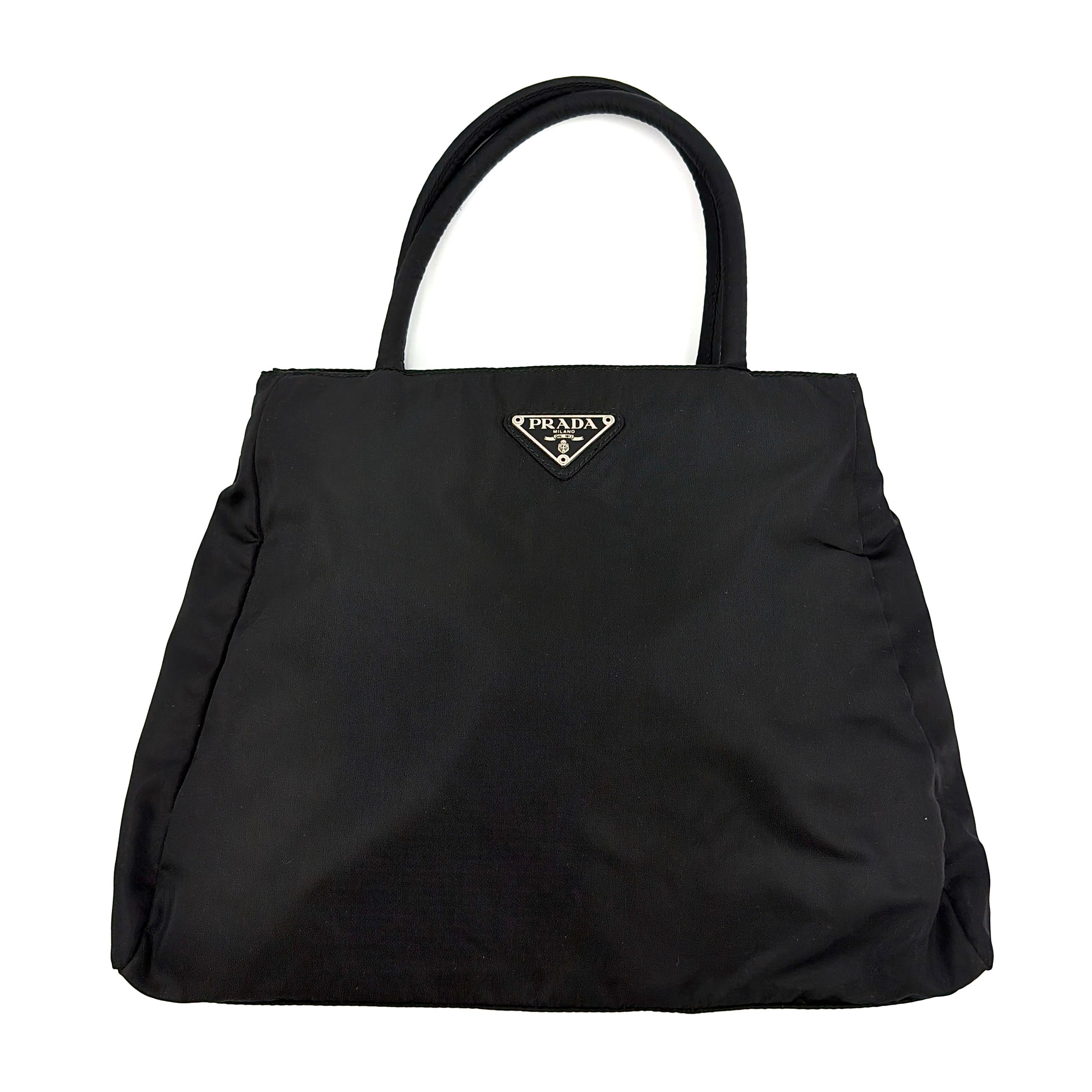 Prada Tessuto Nylon City Tote Bag in black with a structured silhouette, dual rolled handles, and a prominent Prada triangle logo plaque.