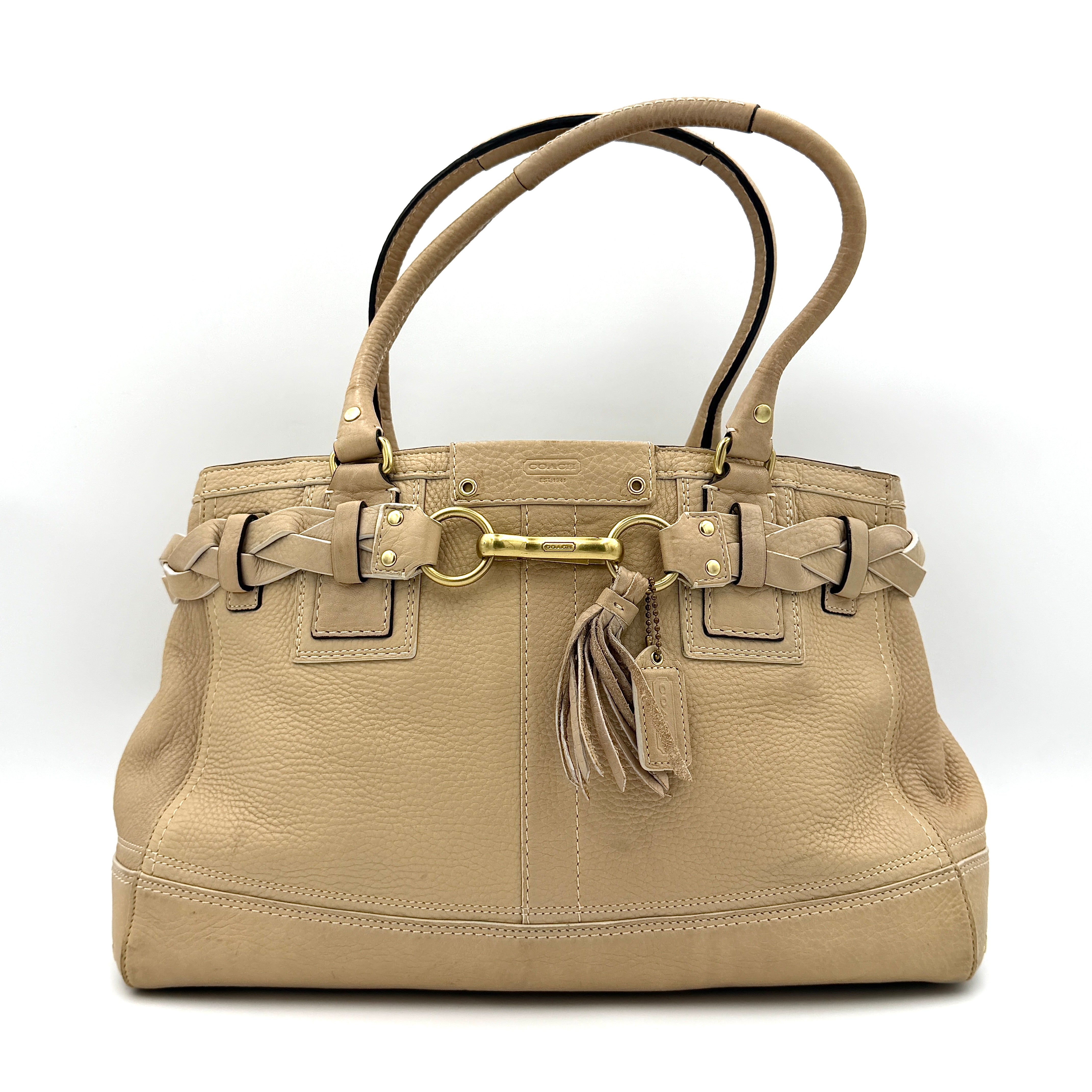 Coach beige Hampton Carryall Shoulder Bag with braided leather details, gold hardware, and tassel accent, displayed front-facing.