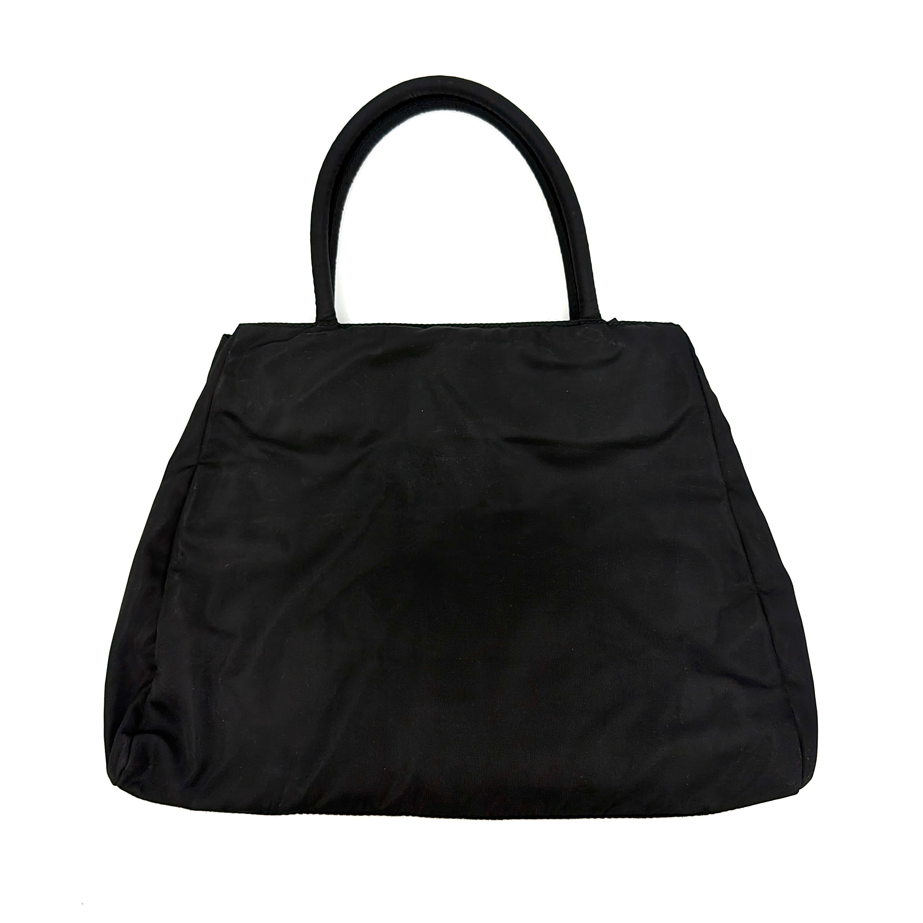 Prada Tessuto Nylon City Tote Bag in black with a structured silhouette, dual rolled handles, and a prominent Prada triangle logo plaque.