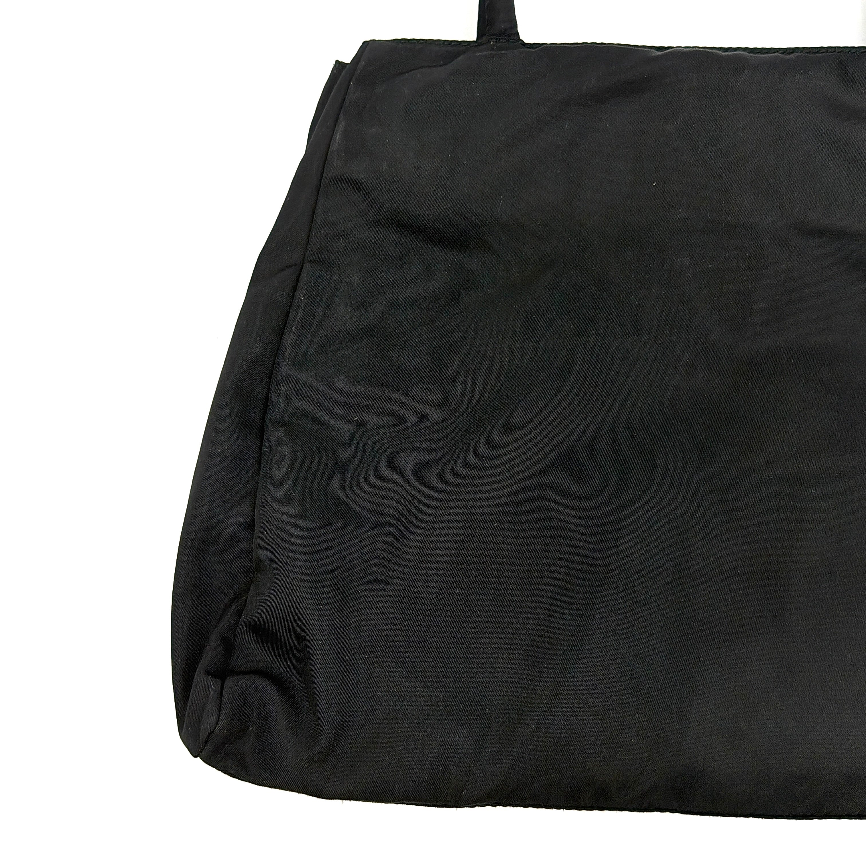 Prada Tessuto Nylon City Tote Bag in black with a structured silhouette, dual rolled handles, and a prominent Prada triangle logo plaque.
