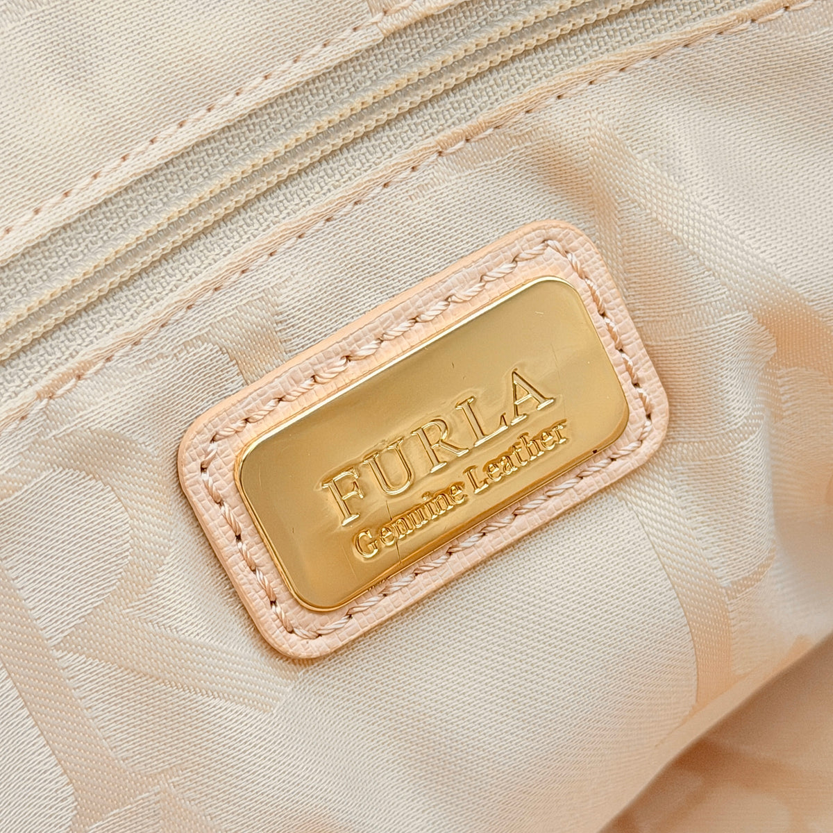 Furla Elena 2Way Saffiano leather satchel in beige with gold-tone hardware and removable strap, displayed on Furla-branded dust bag.
