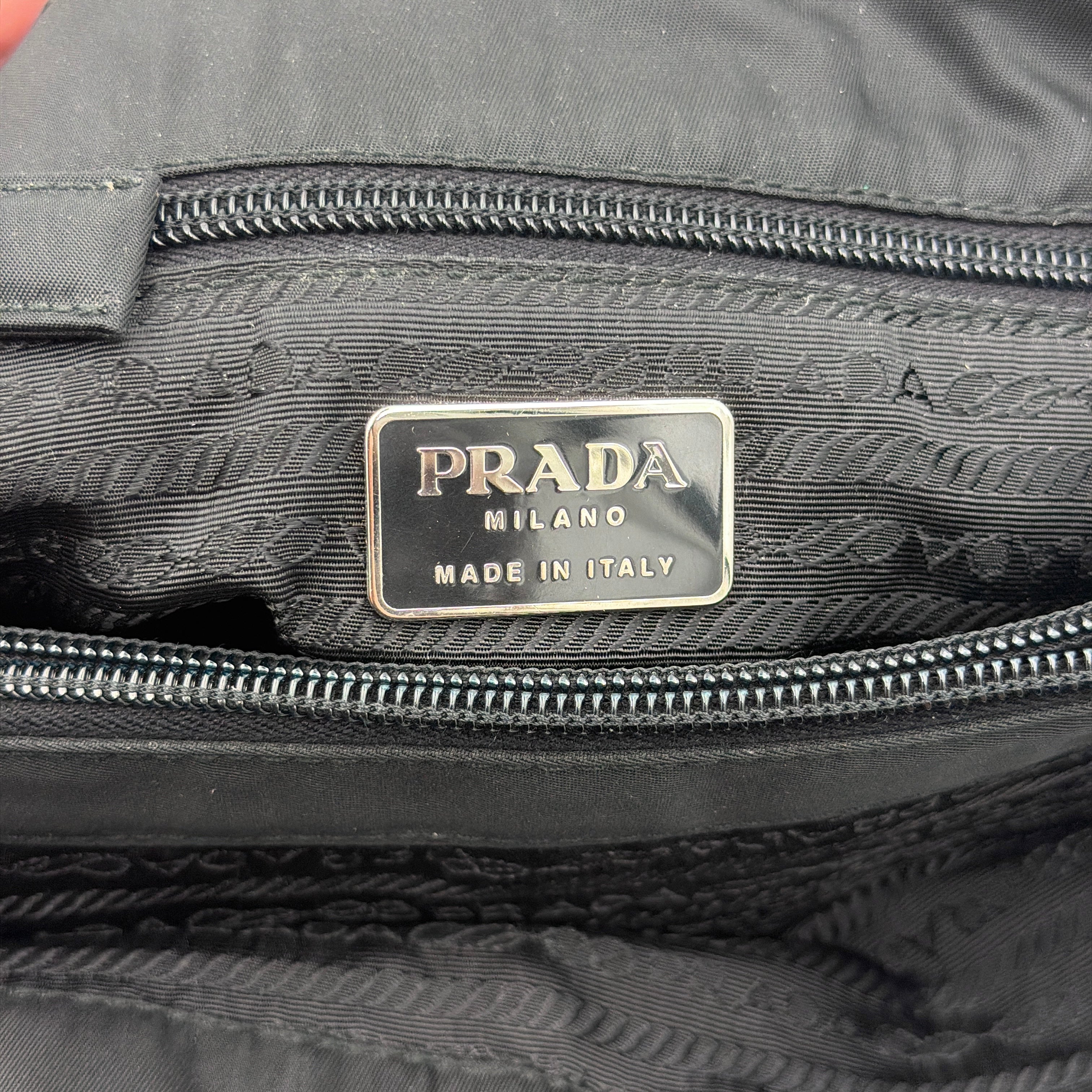 Prada Tessuto Nylon City Tote Bag in black with a structured silhouette, dual rolled handles, and a prominent Prada triangle logo plaque.
