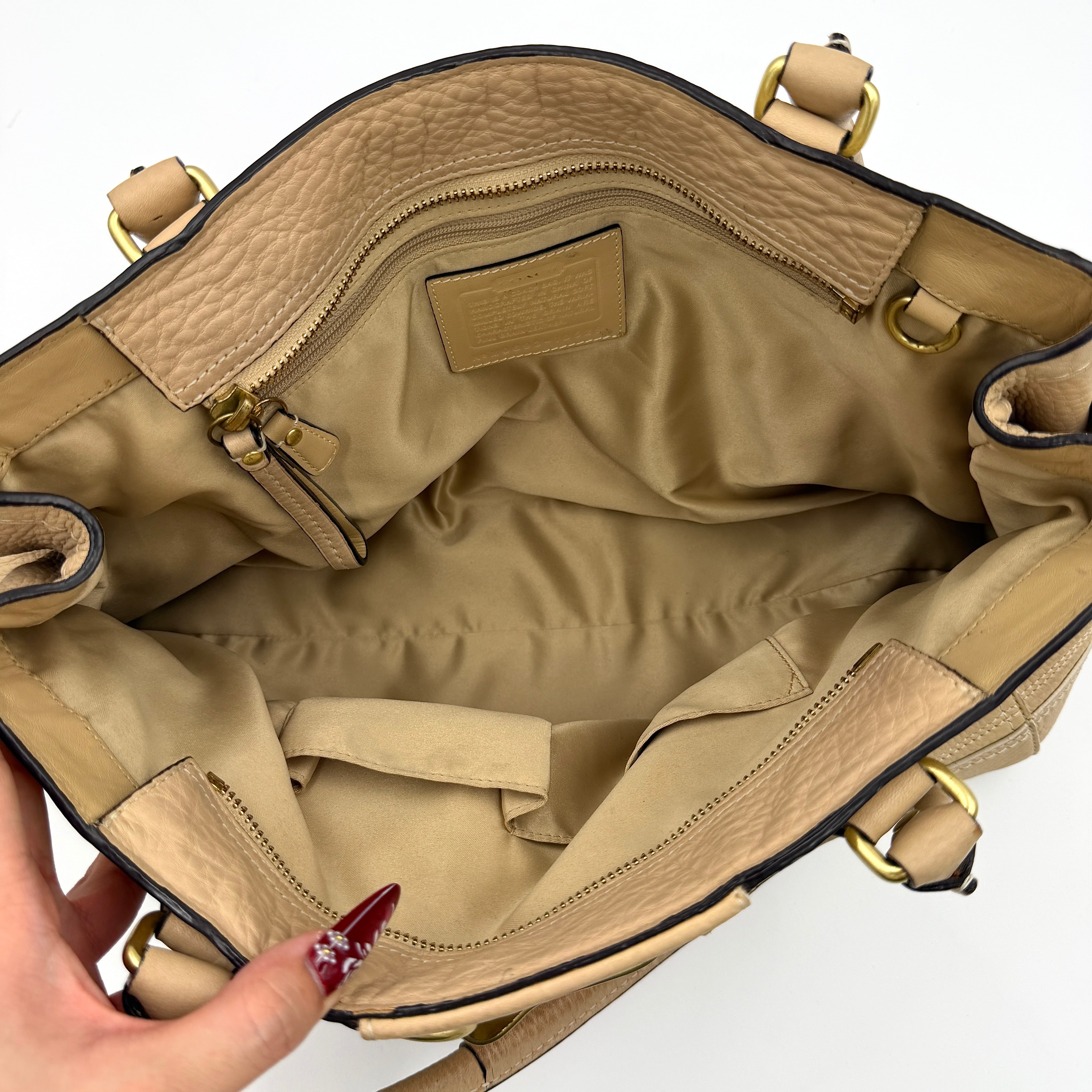 Coach beige Hampton Carryall Shoulder Bag with braided leather details, gold hardware, and tassel accent, displayed front-facing.