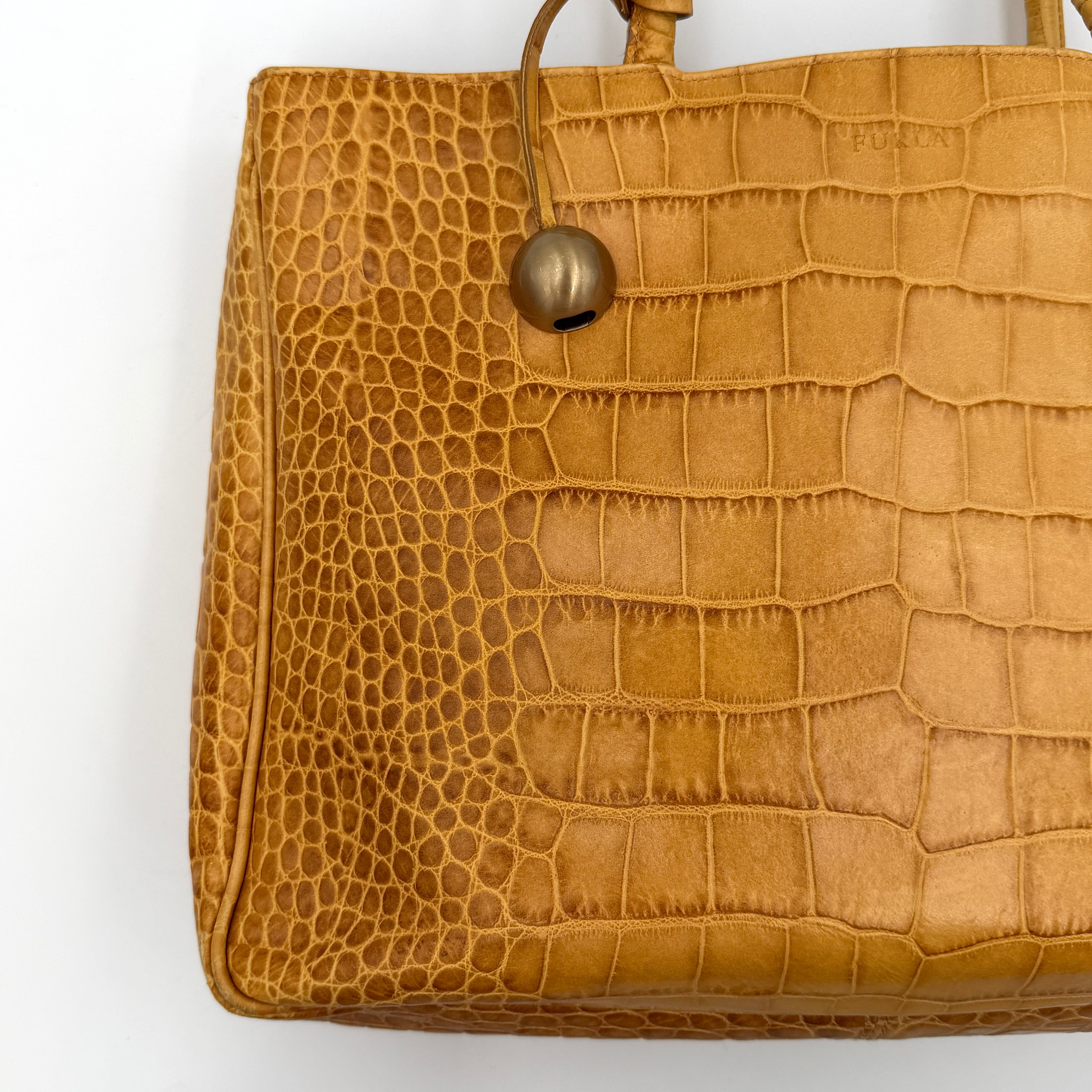 Furla yellow croc-embossed leather tote bag with double handles and matte gold logo charm, presented against a white background.