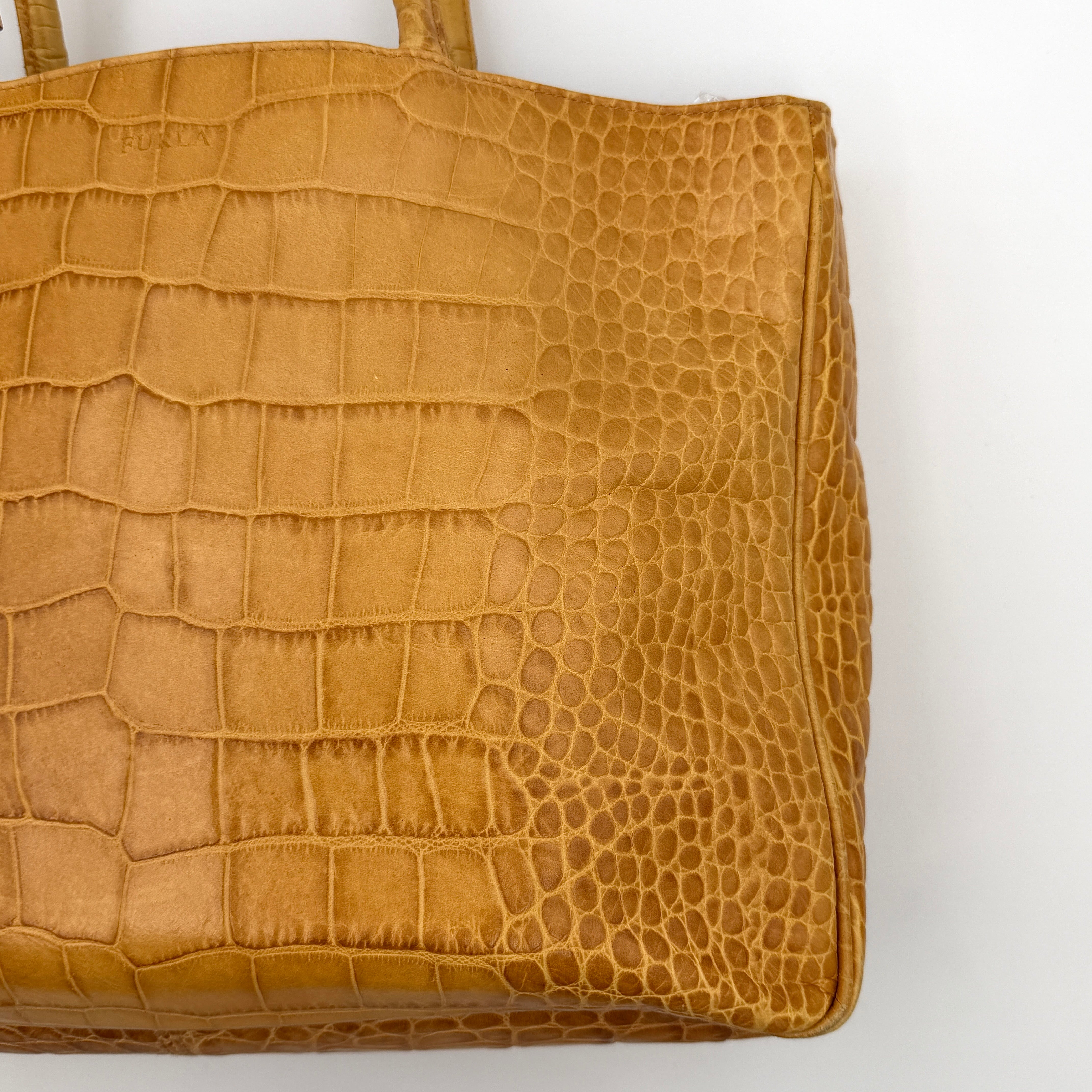 Furla yellow croc-embossed leather tote bag with double handles and matte gold logo charm, presented against a white background.