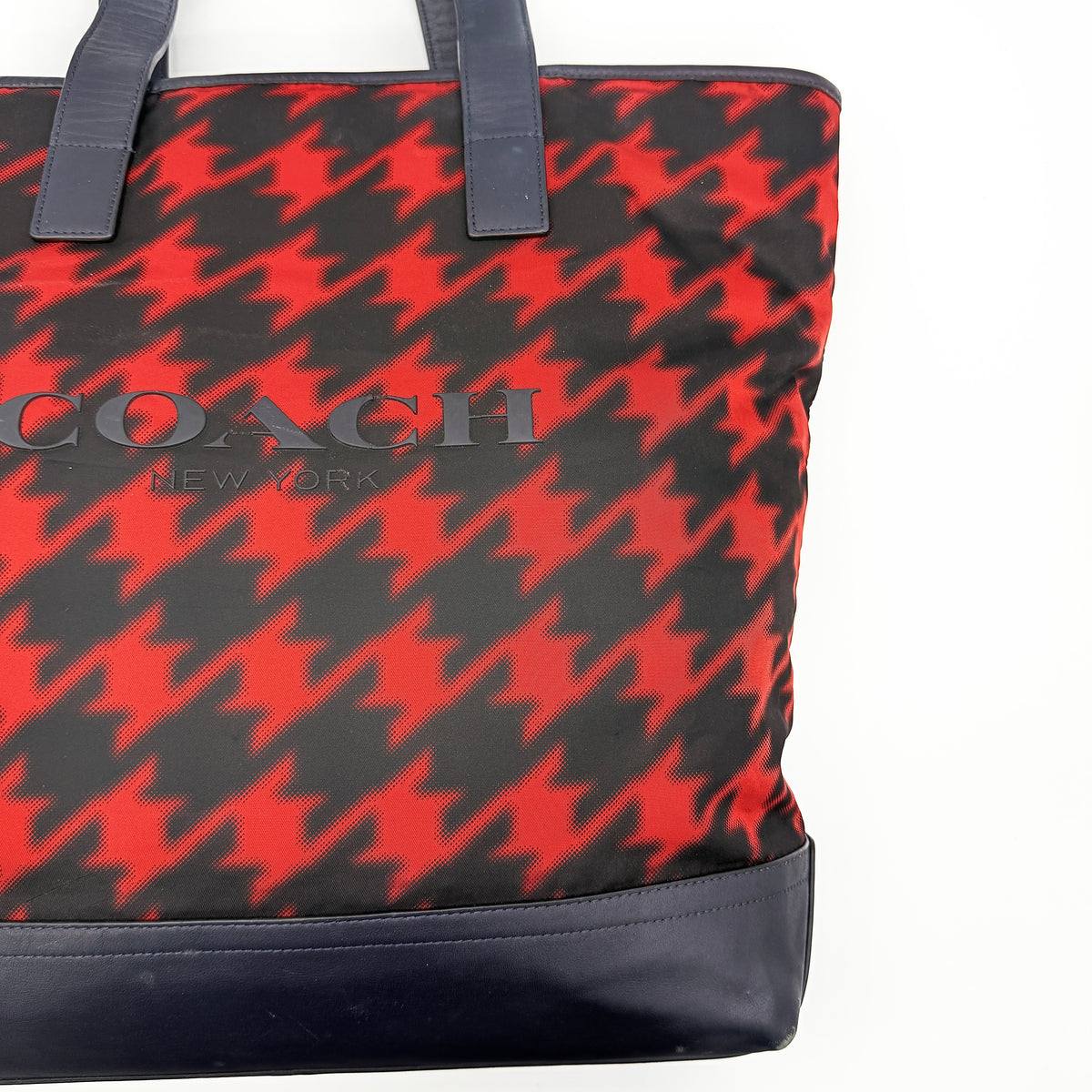 Coach Mercer Print Houndstooth Tote Bag in red and black with leather trim and handles, photographed upright against a white background.