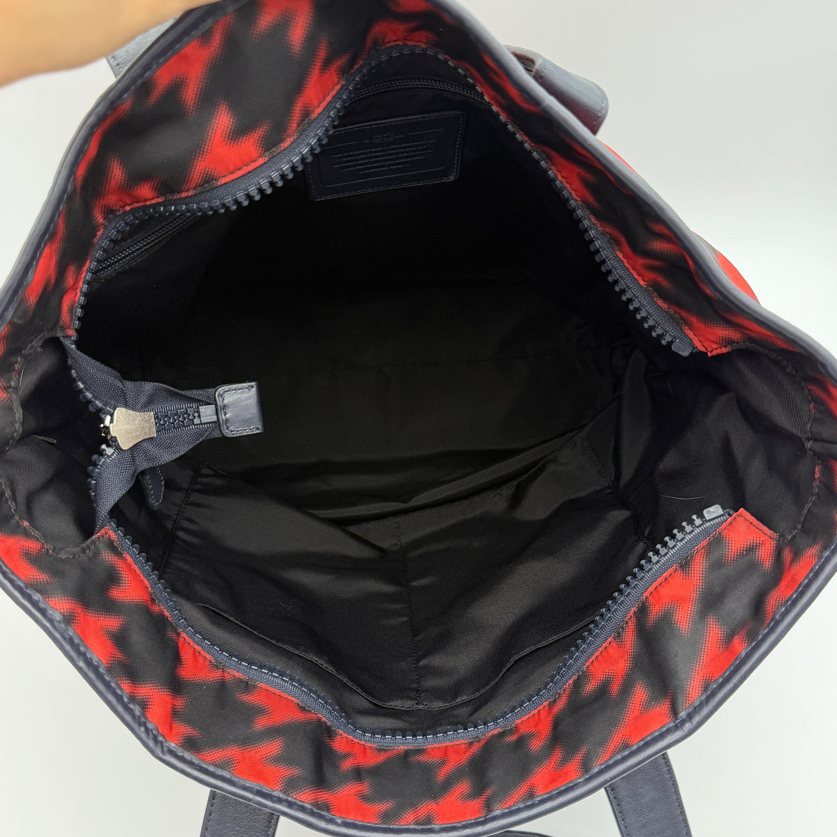 Coach Mercer Print Houndstooth Tote Bag in red and black with leather trim and handles, photographed upright against a white background.