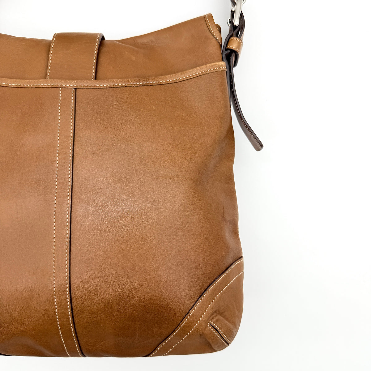Coach Soho Buckle Flap Crossbody Bag in brown leather with buckle flap and adjustable strap, displayed on white background.